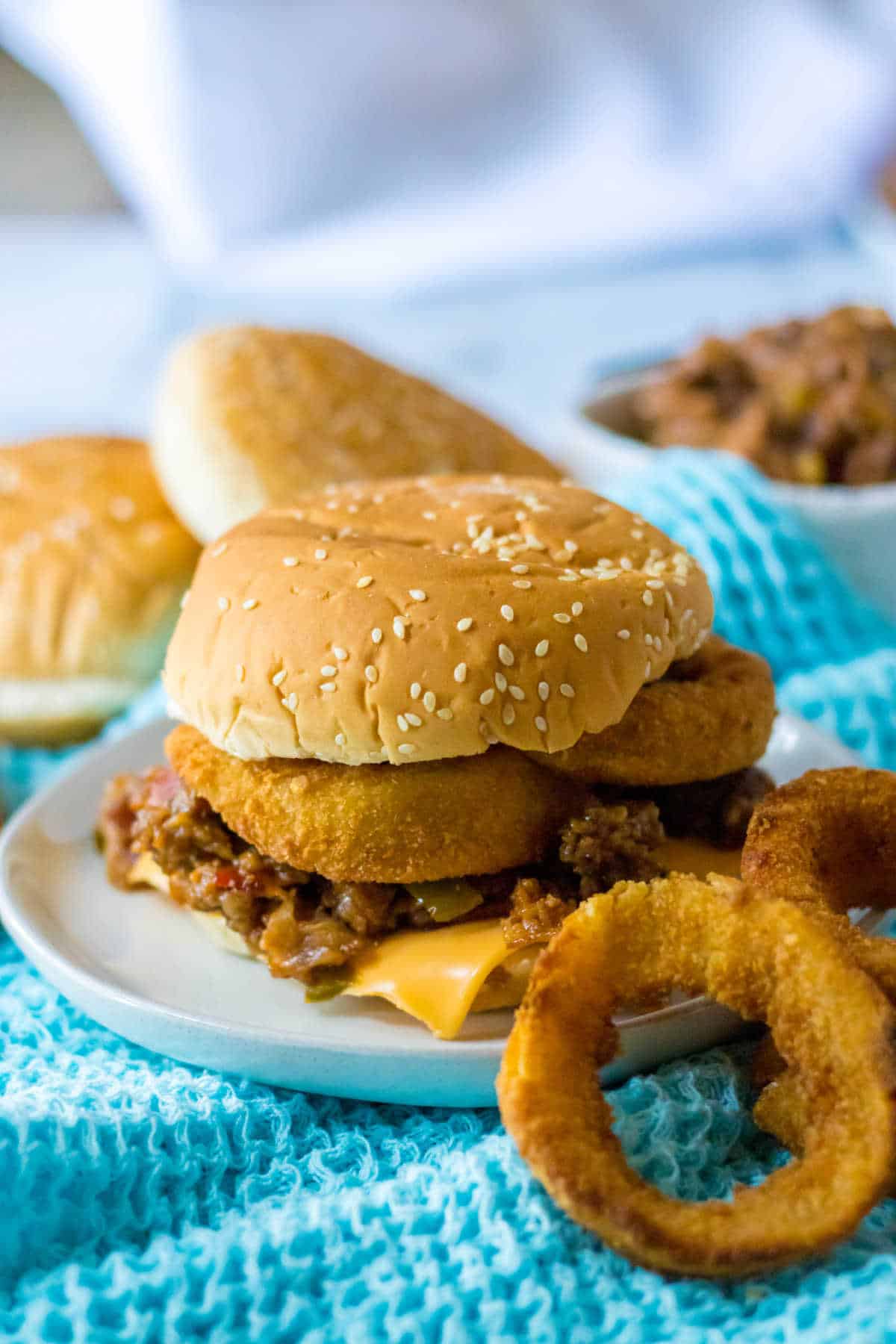 A rodeo sloppy joe on a plate with onion rings.