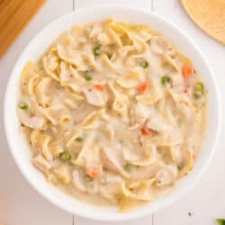 A white bowl of creamy chicken noodle soup.