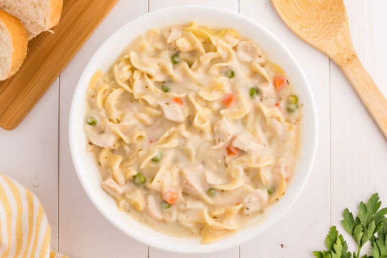 A white bowl of creamy chicken noodle soup.