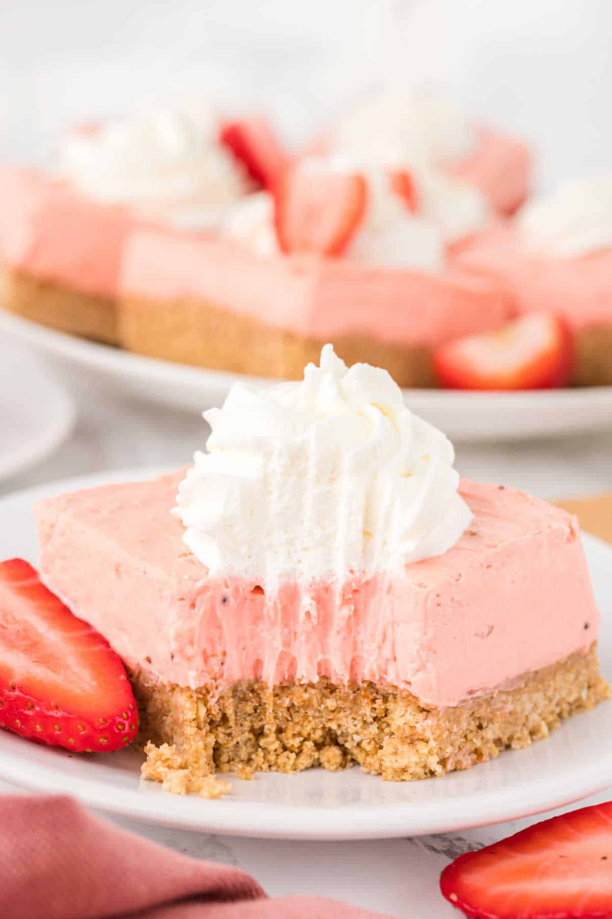 A strawberry cheesecake bar on plate with a bite out of it.