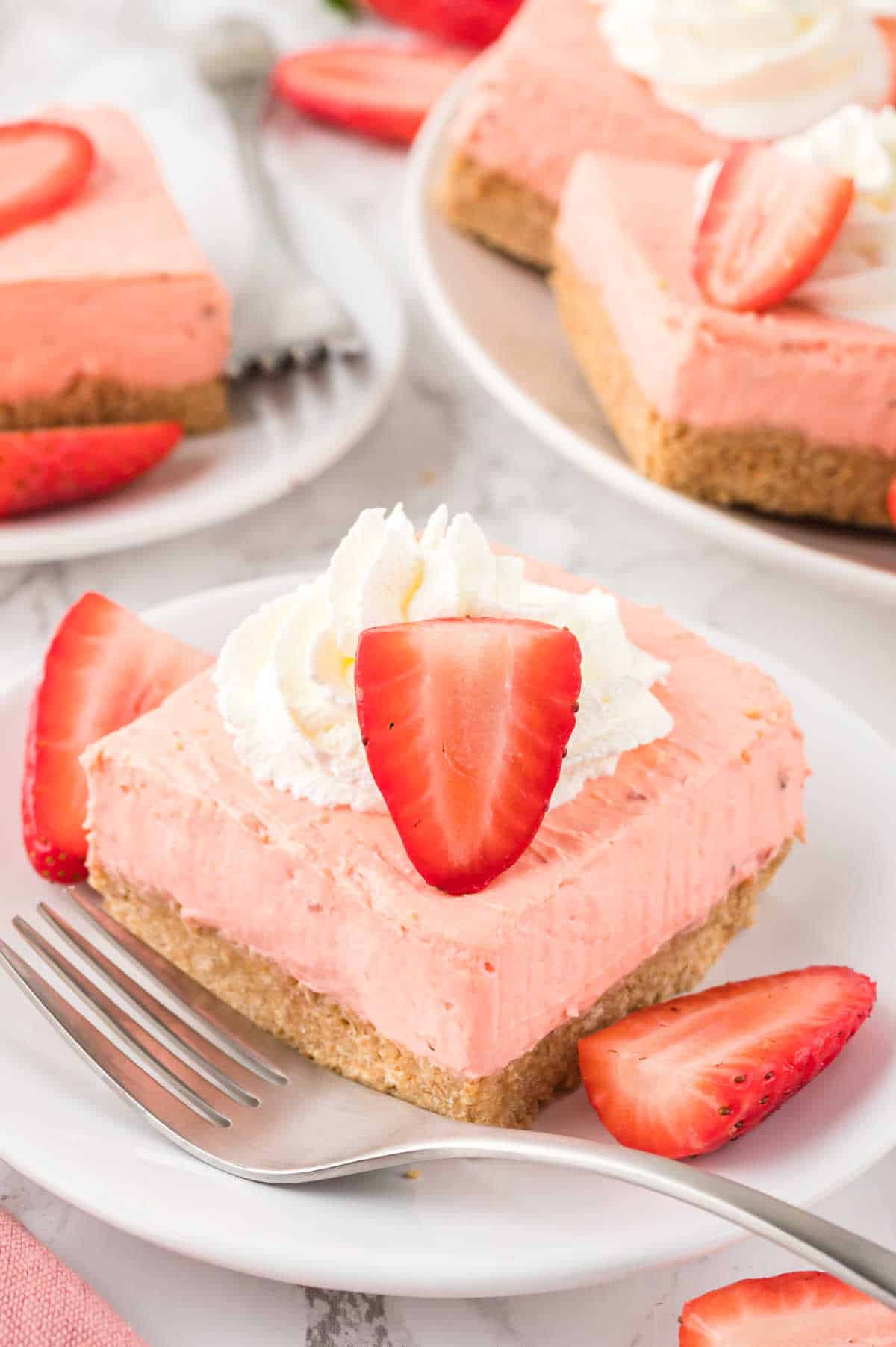 A strawberry cheesecake bar on a plate with a fork.