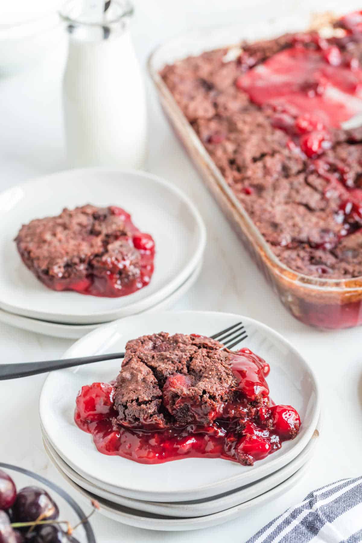 A piece of black forest dump cake on a plate with a fork.