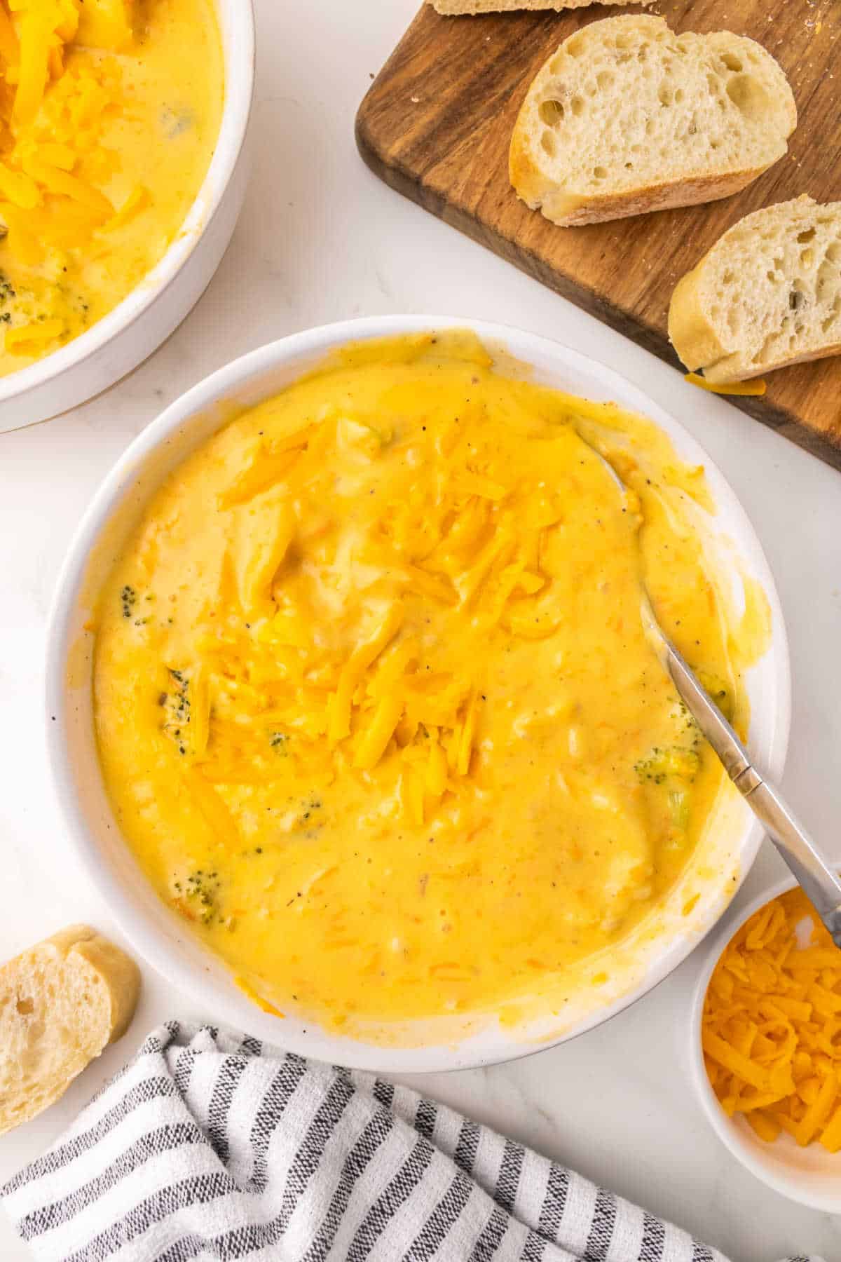 A bowl of broccoli cheddar soup with a spoon.
