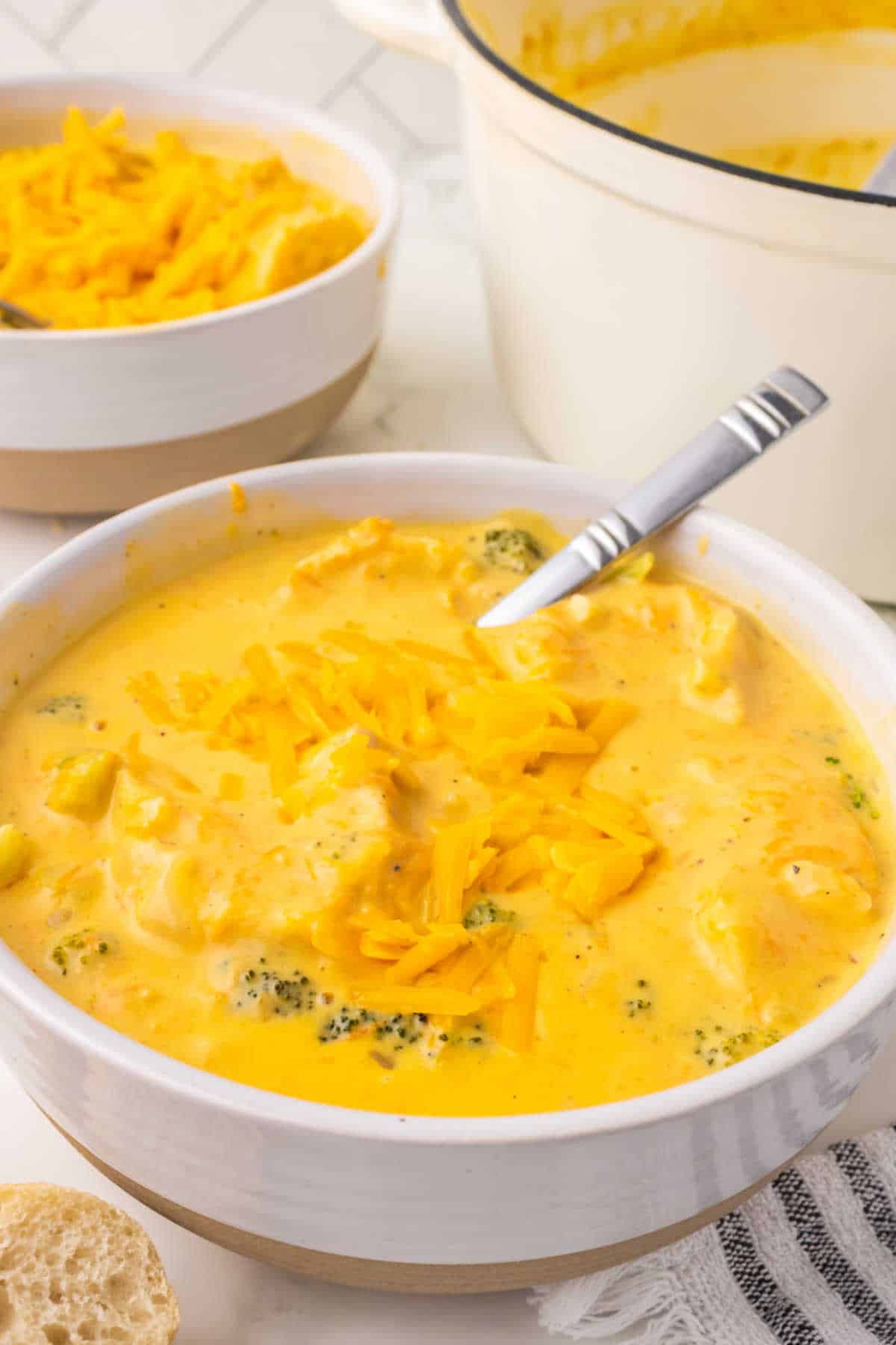 A bowl of broccoli cheddar soup with a spoon.