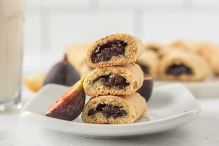 A stack of cookies on a plate with a sliced fig.