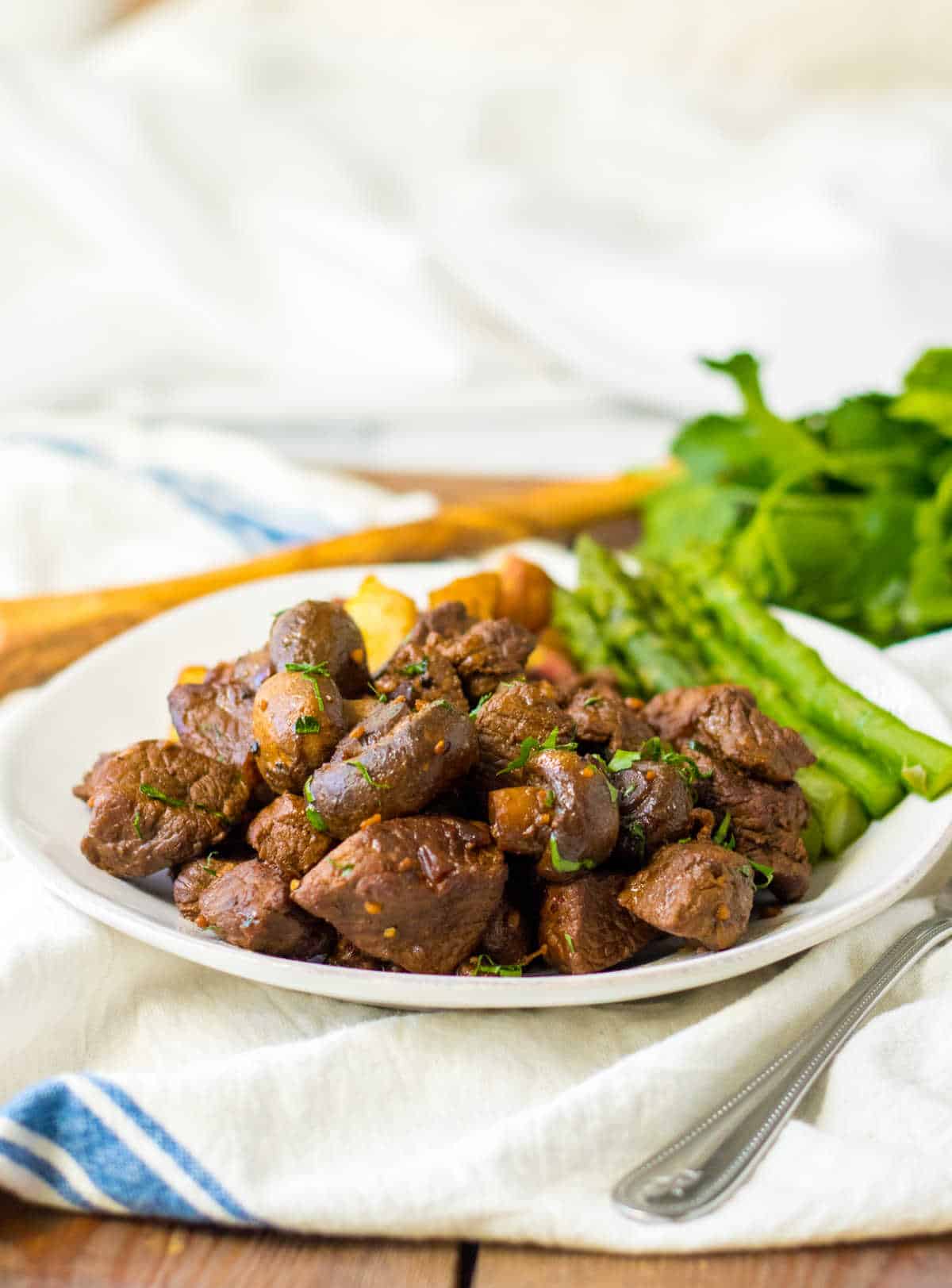 Mushroom steak bites on a plate with asparagus and potatoes.