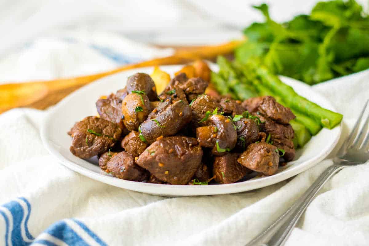 Mushroom steak bites on a plate with asparagus and potaotes.