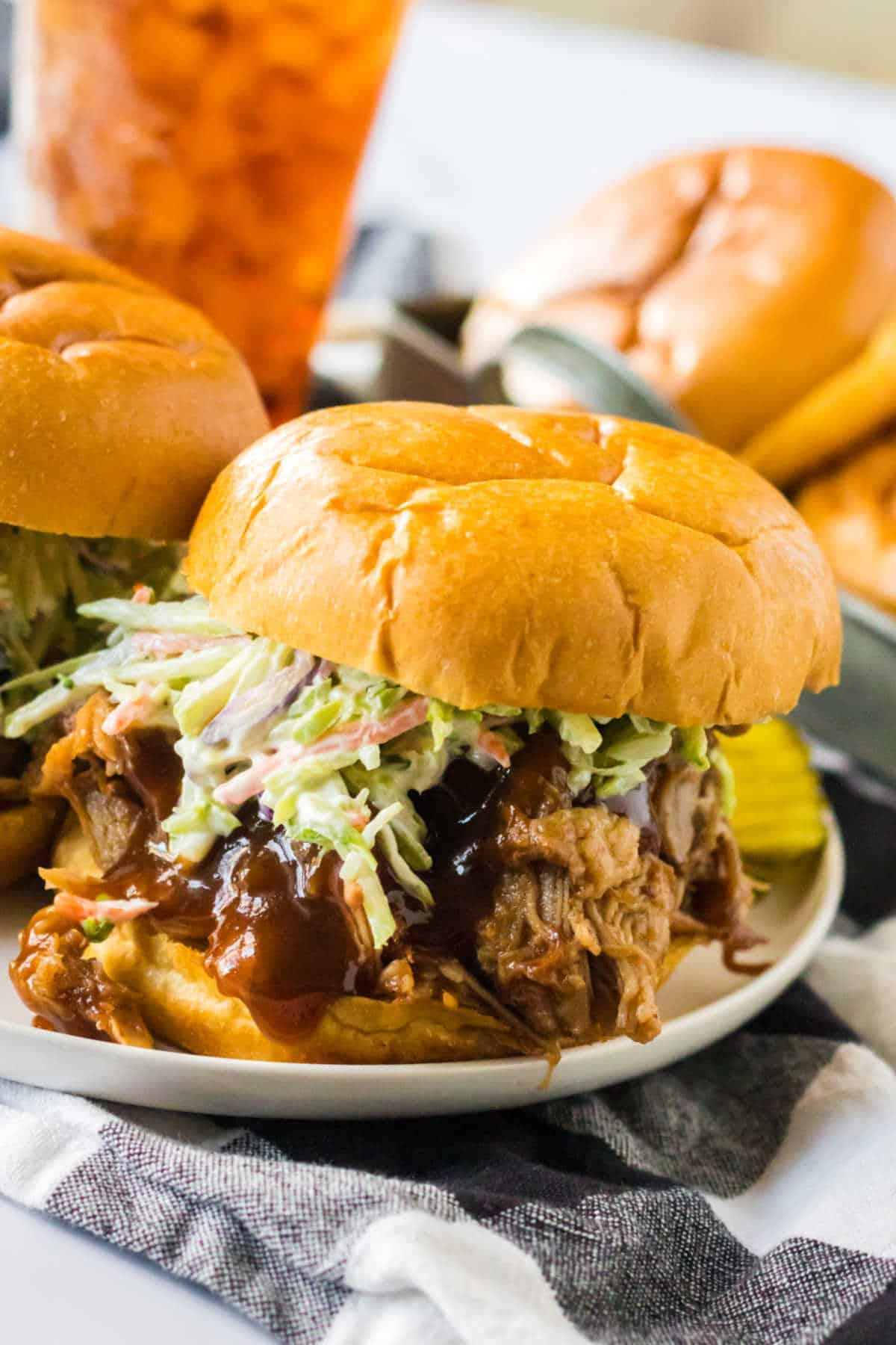 Root beer pulled pork and coleslaw on a bun on a plate.