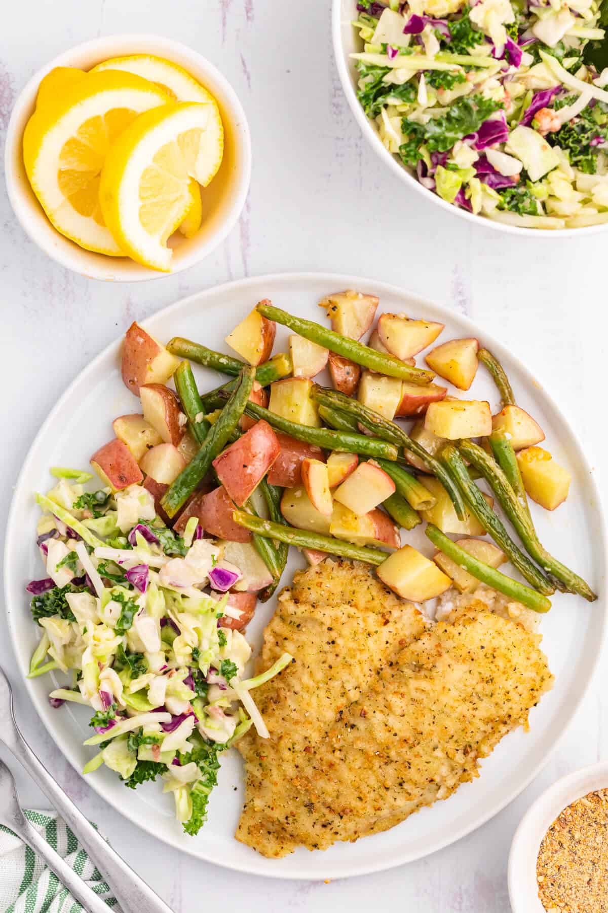 Lemon pepper sole with salad, potatoes and green beans on a plate.