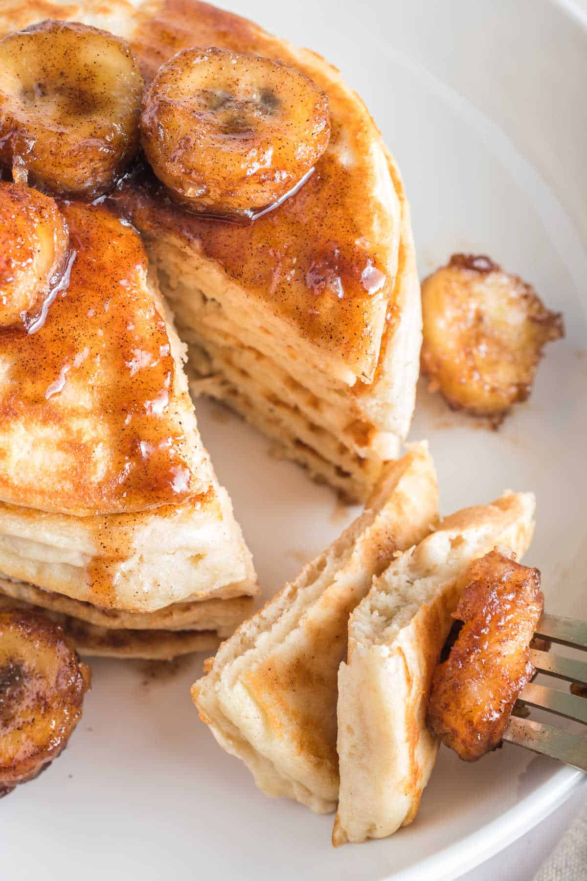 A fork with bananas foster pancakes on it.