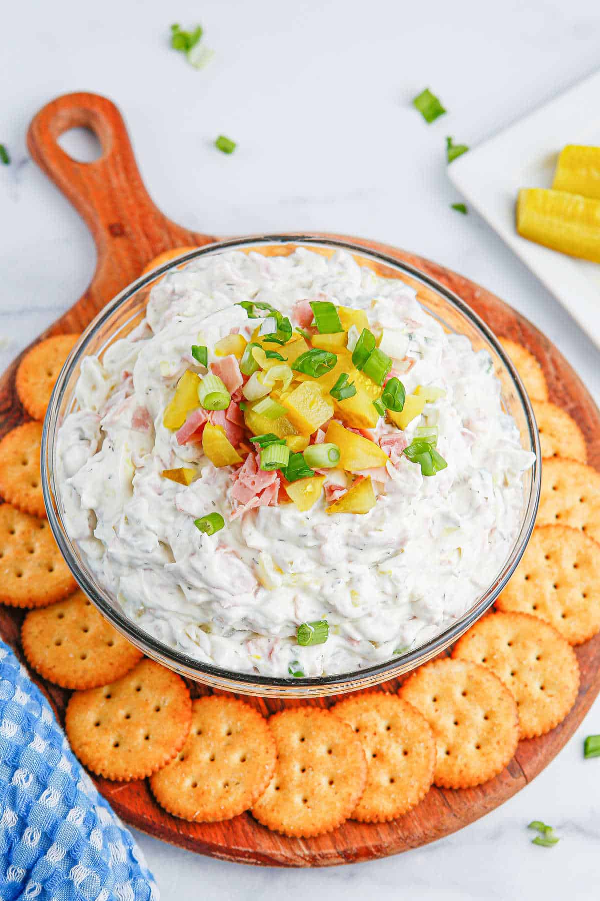 Dill pickle dip in a bowl surrounded by crackers.