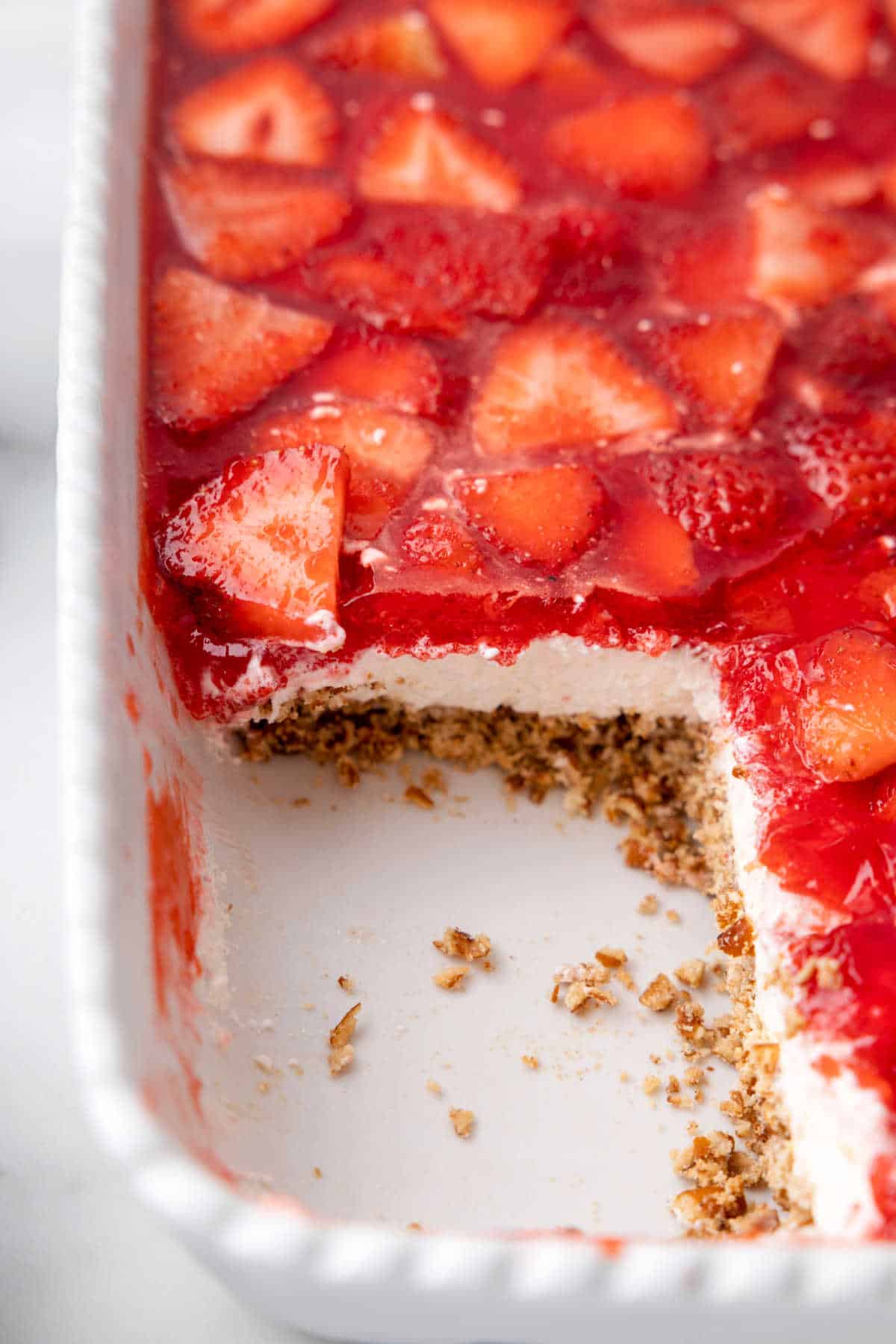 Strawberry pretzel salad in a pan with a piece cut out.