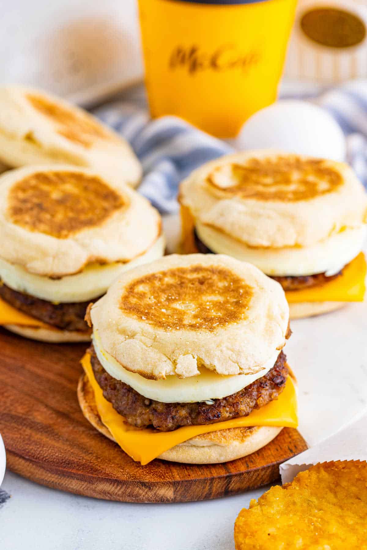 Three breakfast sandwiches on a wooden surface.