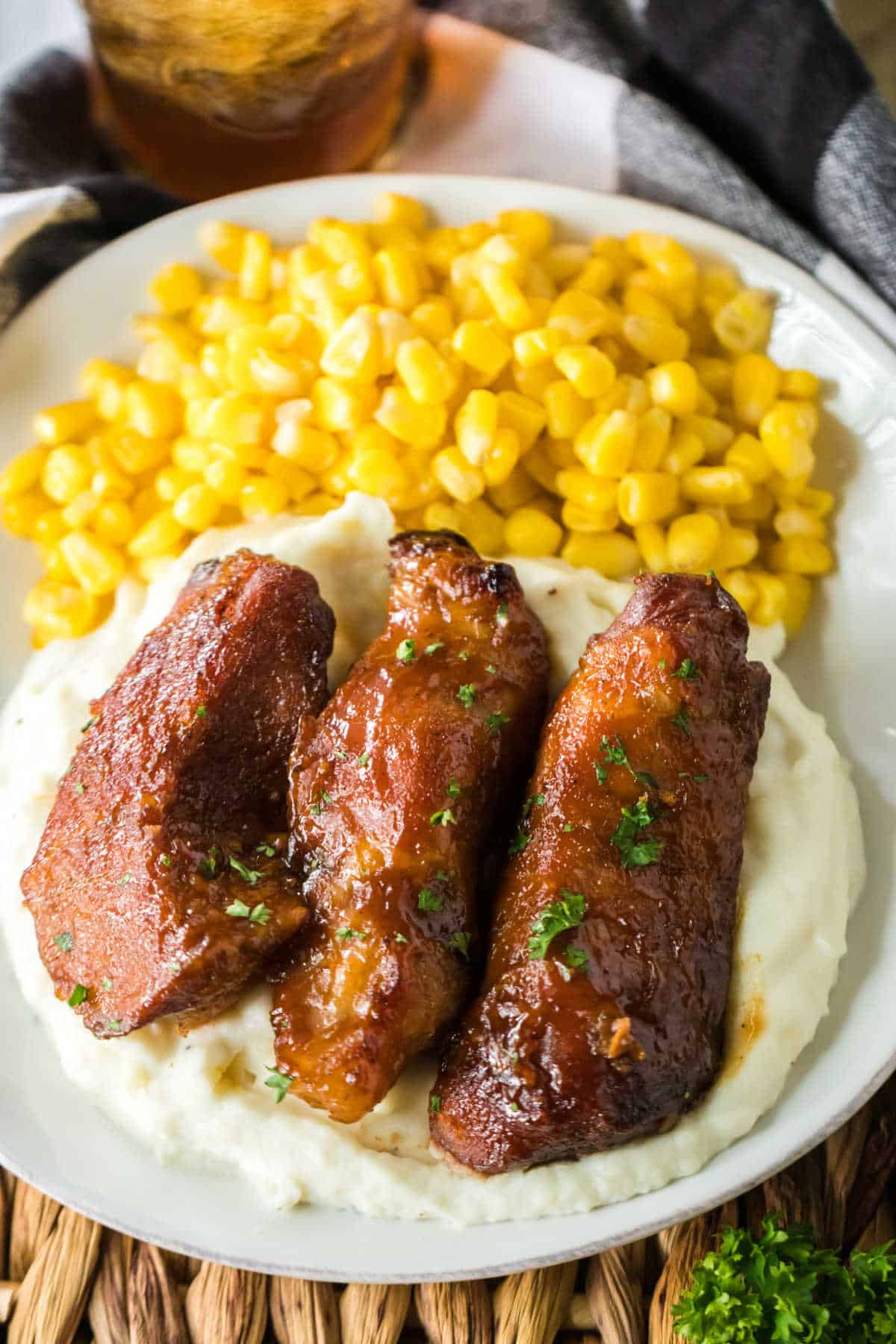 A plate of mashed potatoes, corn and country style ribs.