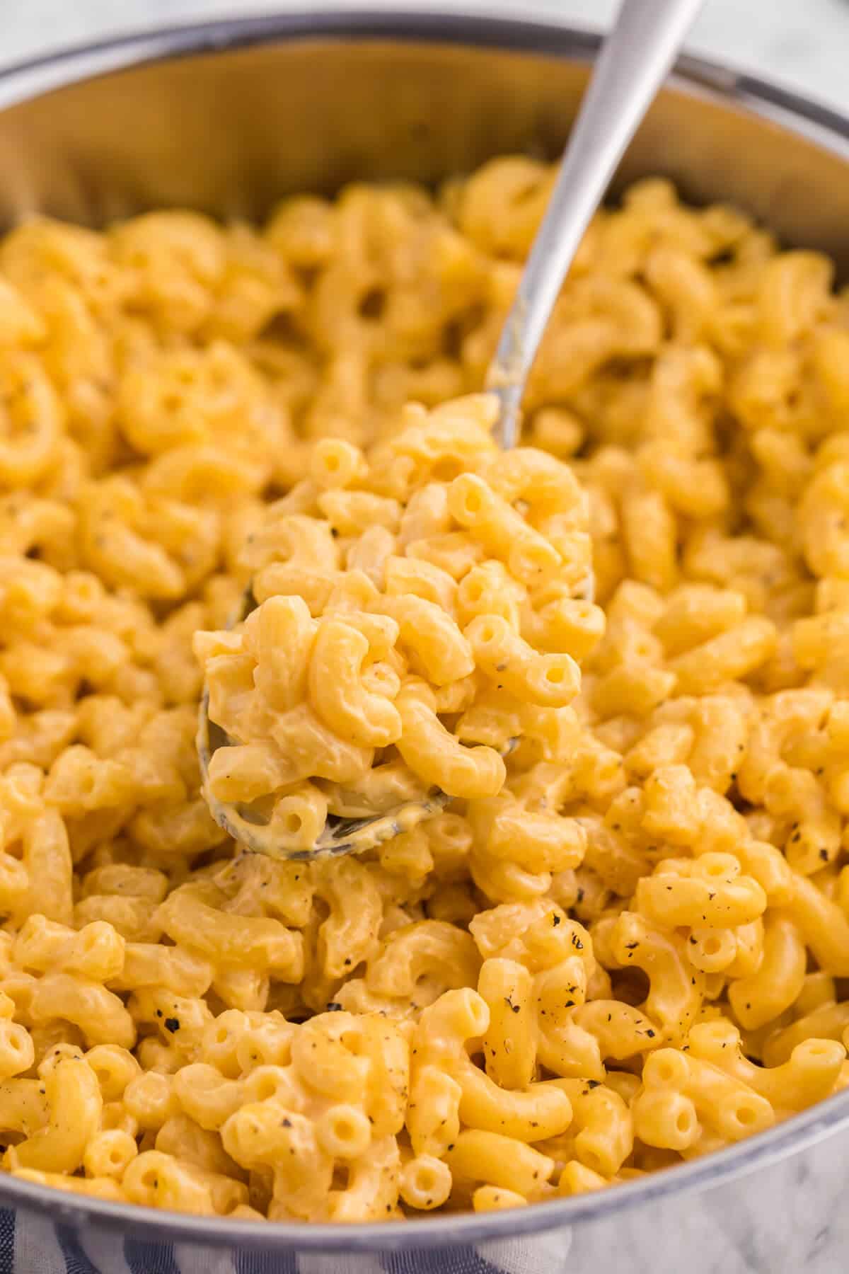 Stovetop mac and cheese in a pot with a serving spoon. 