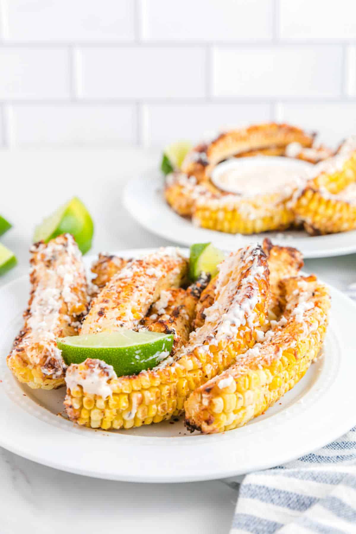 Air fryer corn ribs on a plate with pieces of lime.