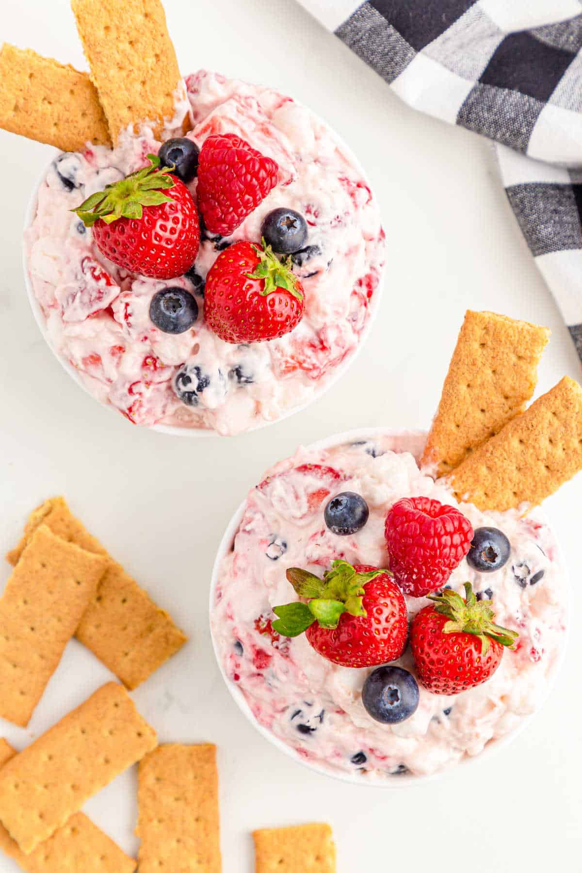 Two bowls of berry cheesecake fluff with graham crackers.