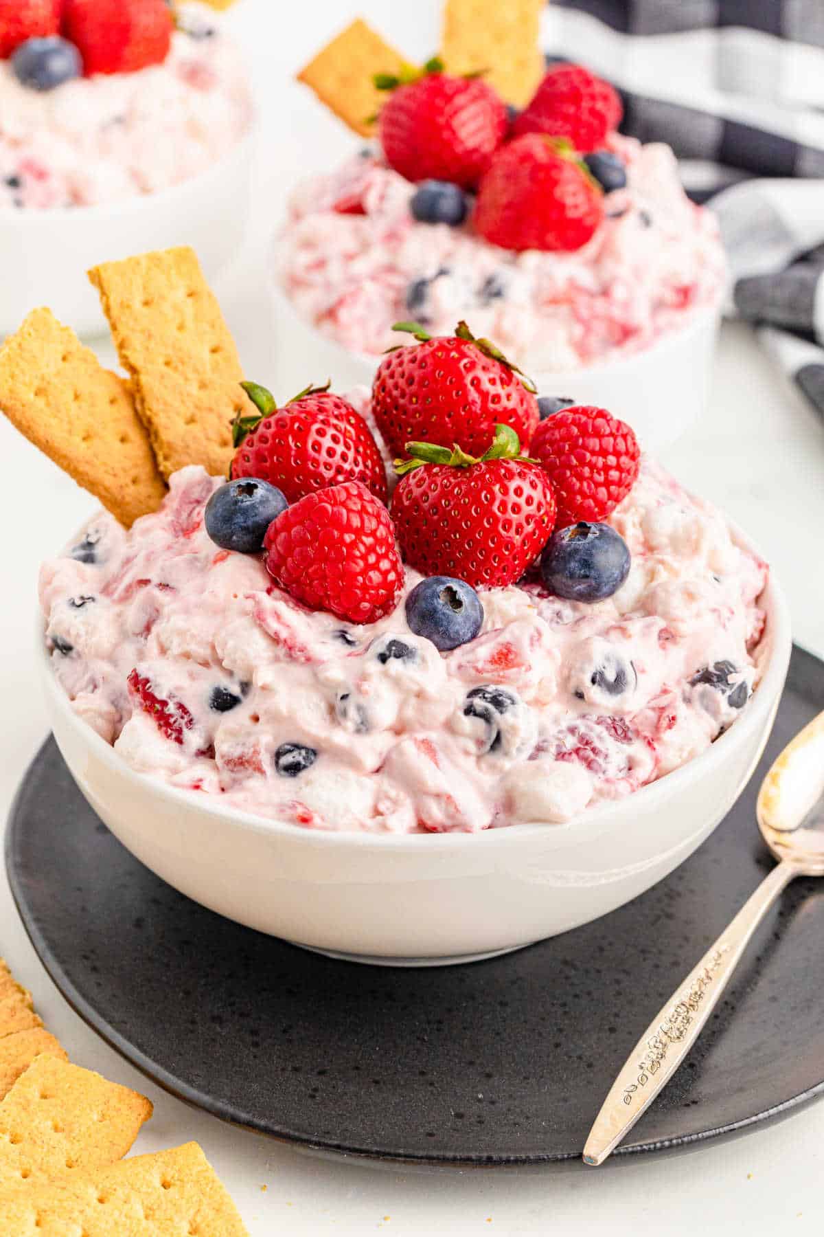 A bowl of berry cheesecake fluff with graham crackers in it.