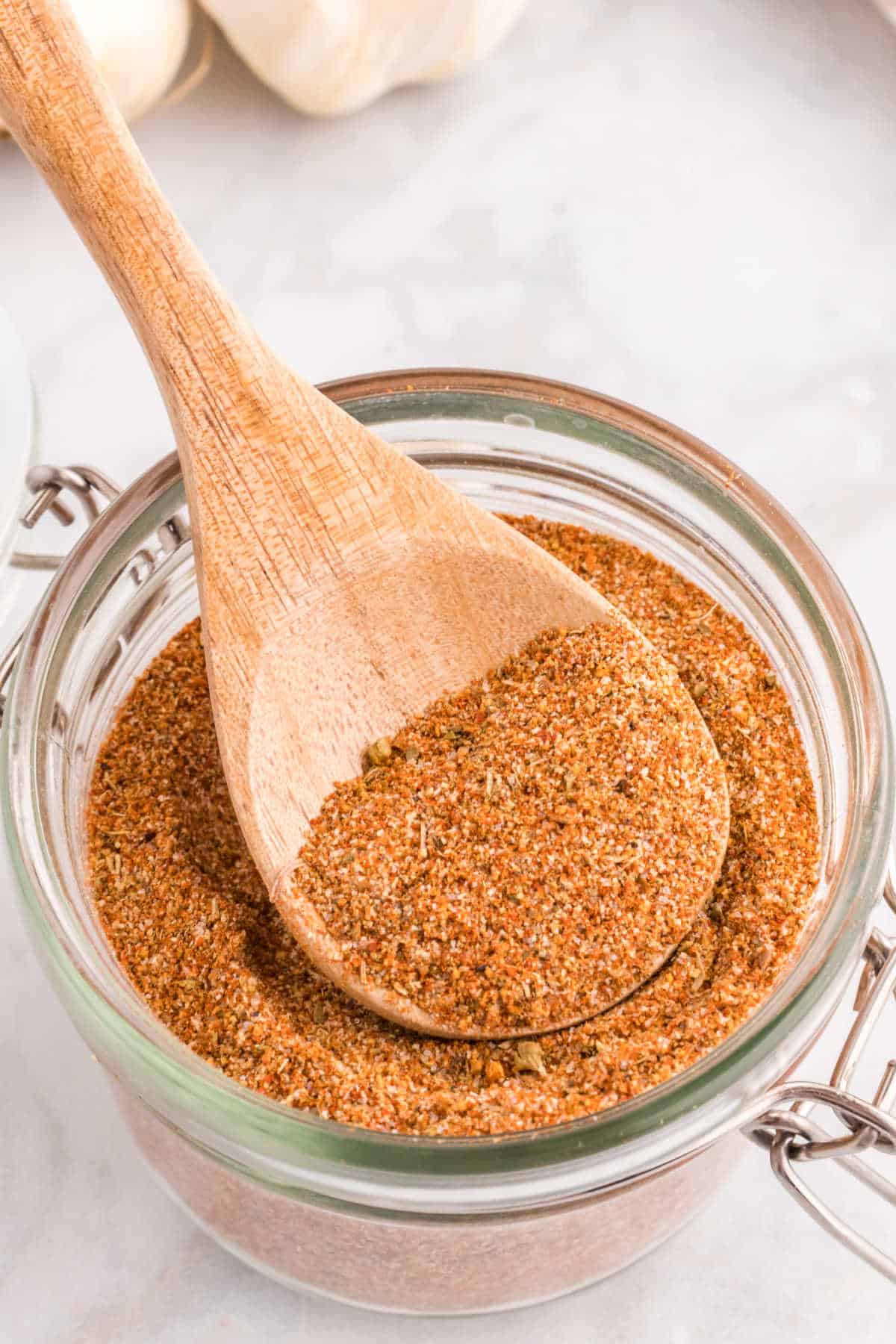 Cajun seasoning in a canister with a wooden spoon.