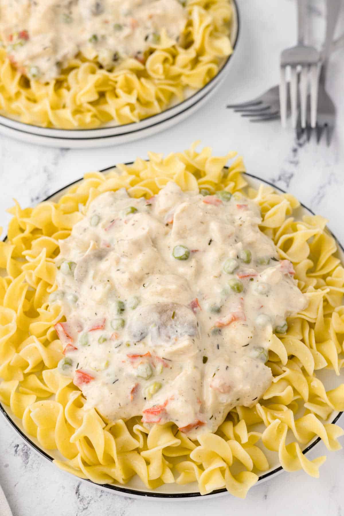 Chicken a la King on a bed of egg noodles on a plate.