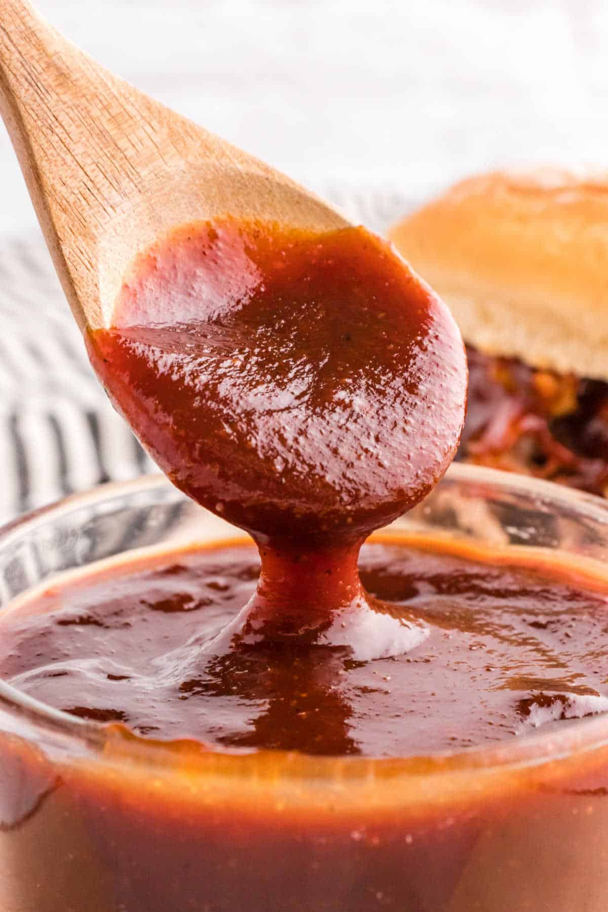 Homemade bbq sauce in a bowl with a wooden spoon.