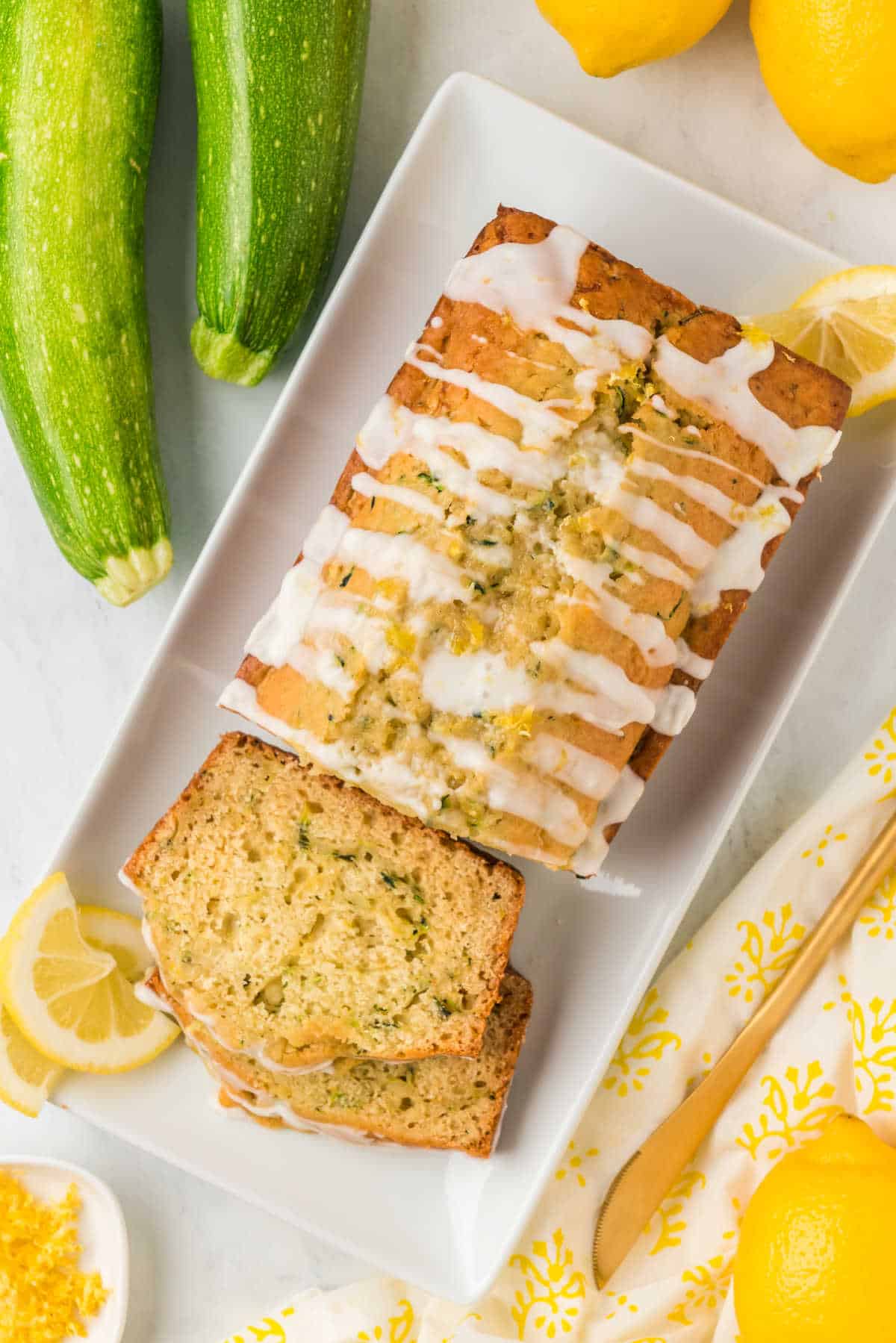 Lemon zucchini bread on a platter with slices cut.
