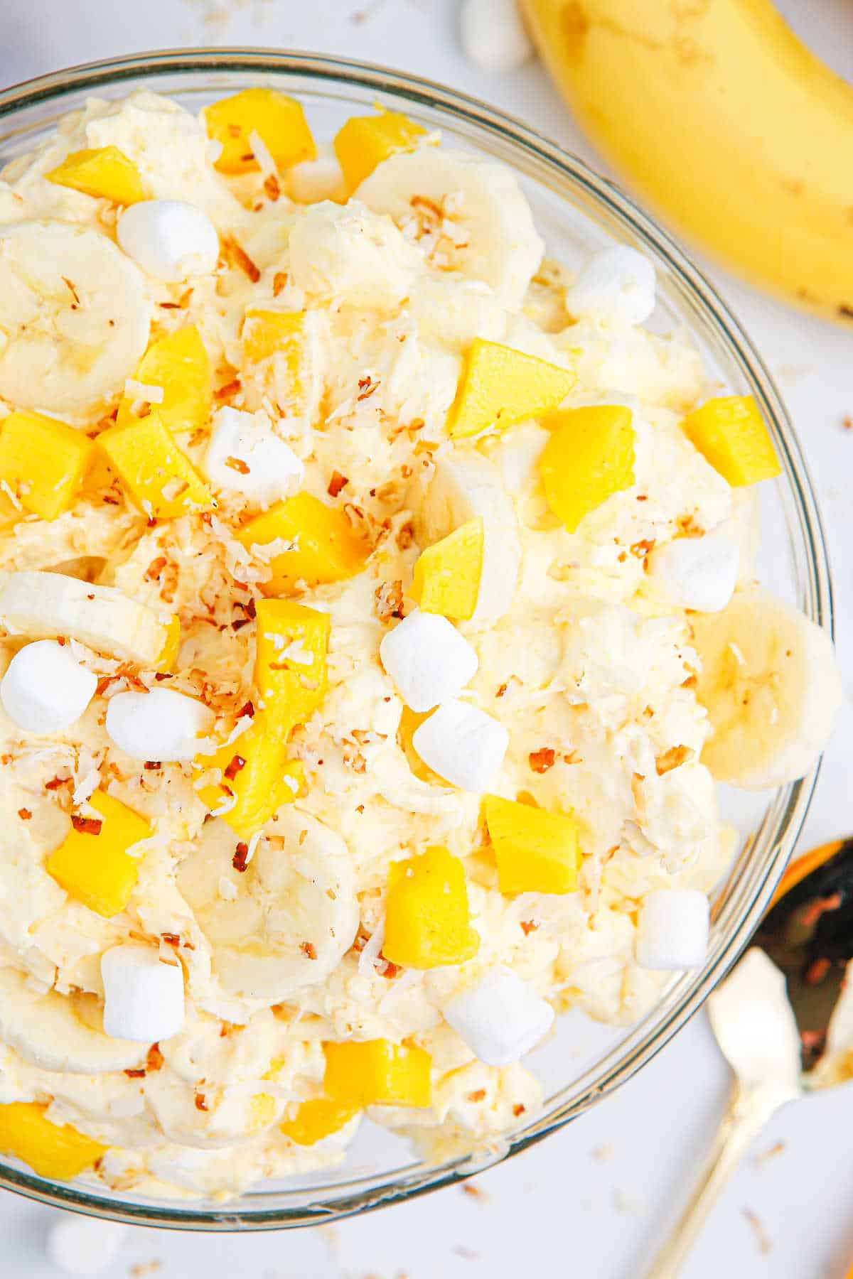 A bowl of mango banana marshmallow salad.