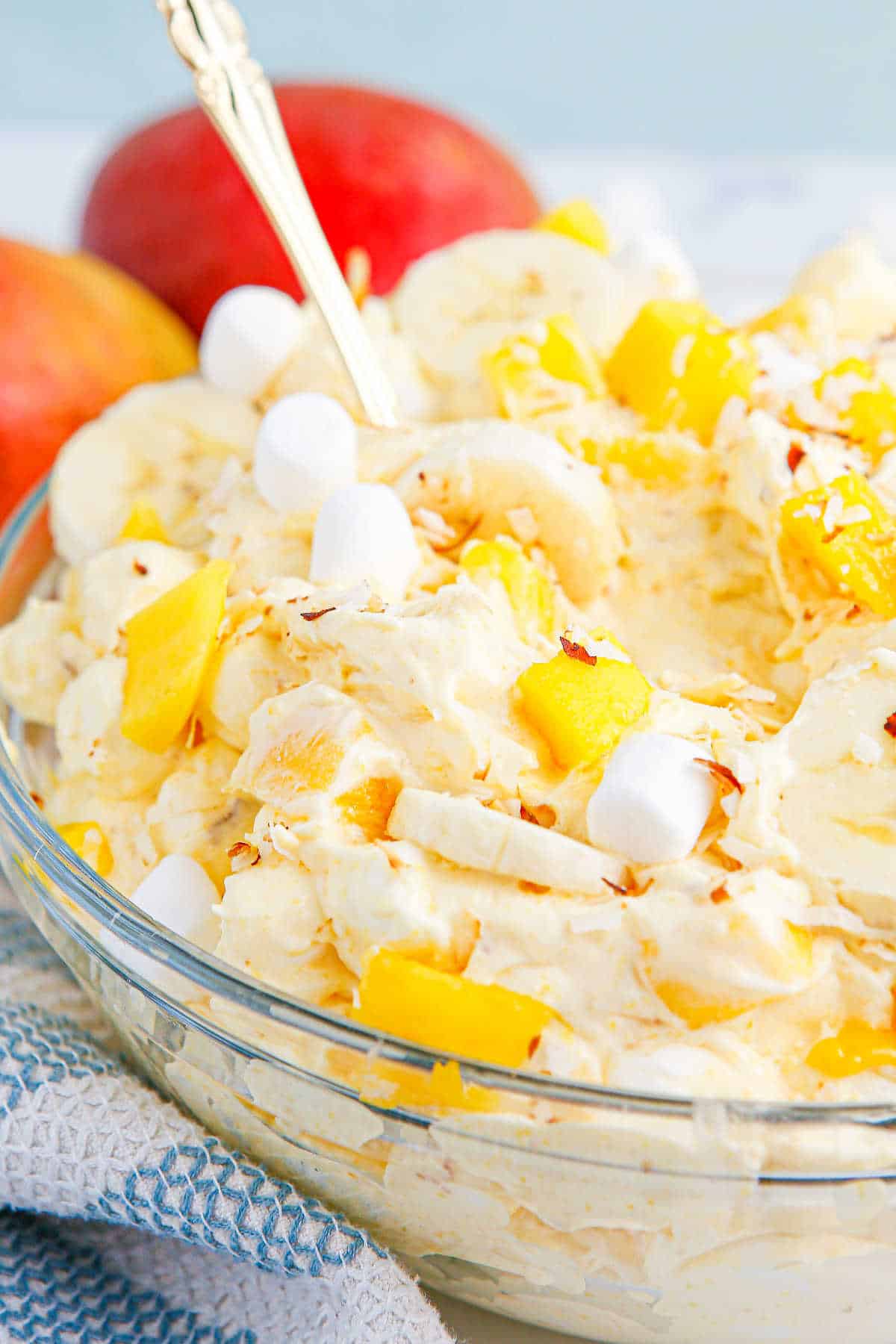 A bowl of mango banana marshmallow salad with a spoon in it.