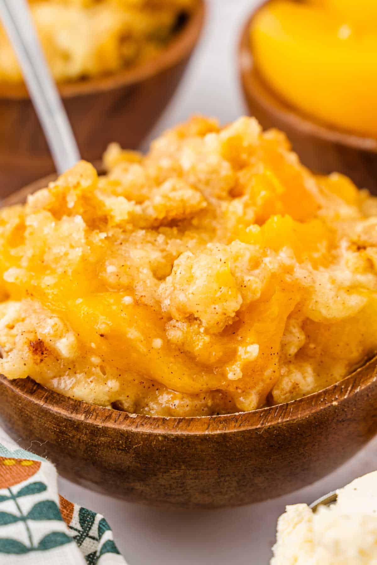 A bowl of peach cobbler dump cake with a spoon.