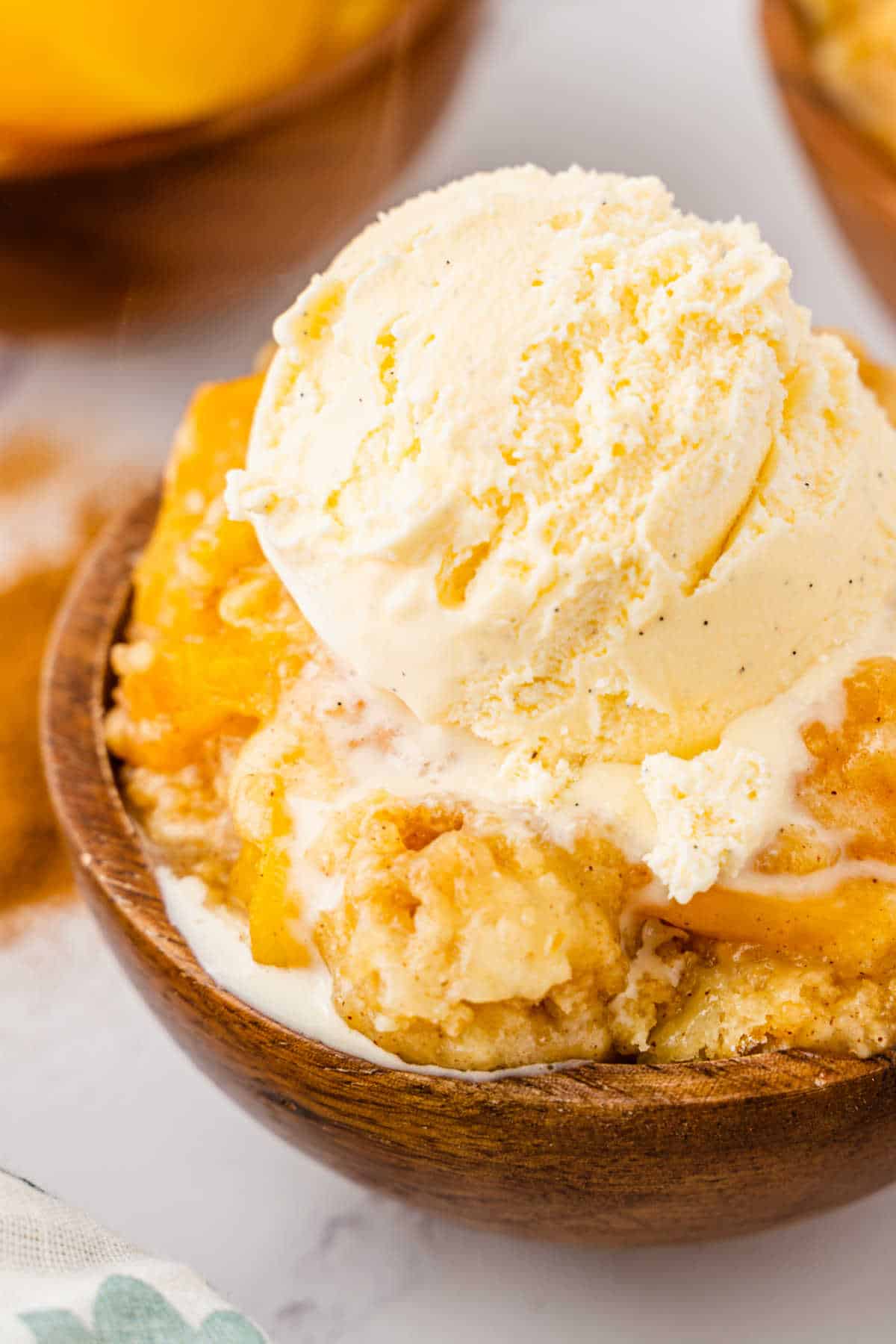 Peach cobbler dump cake in a bowl topped with ice cream.