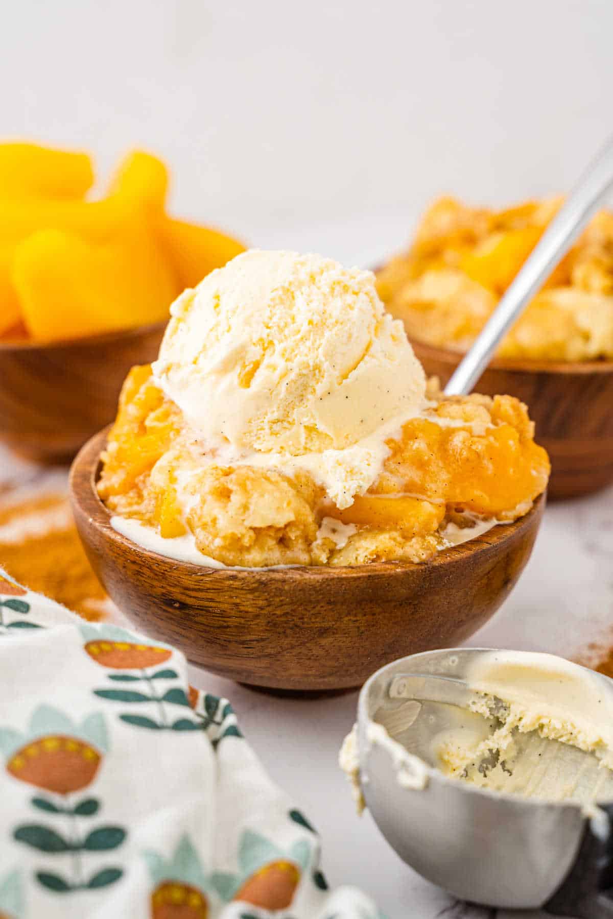 Peach cobbler dump cake in a bowl with a spoon topped with ice cream.