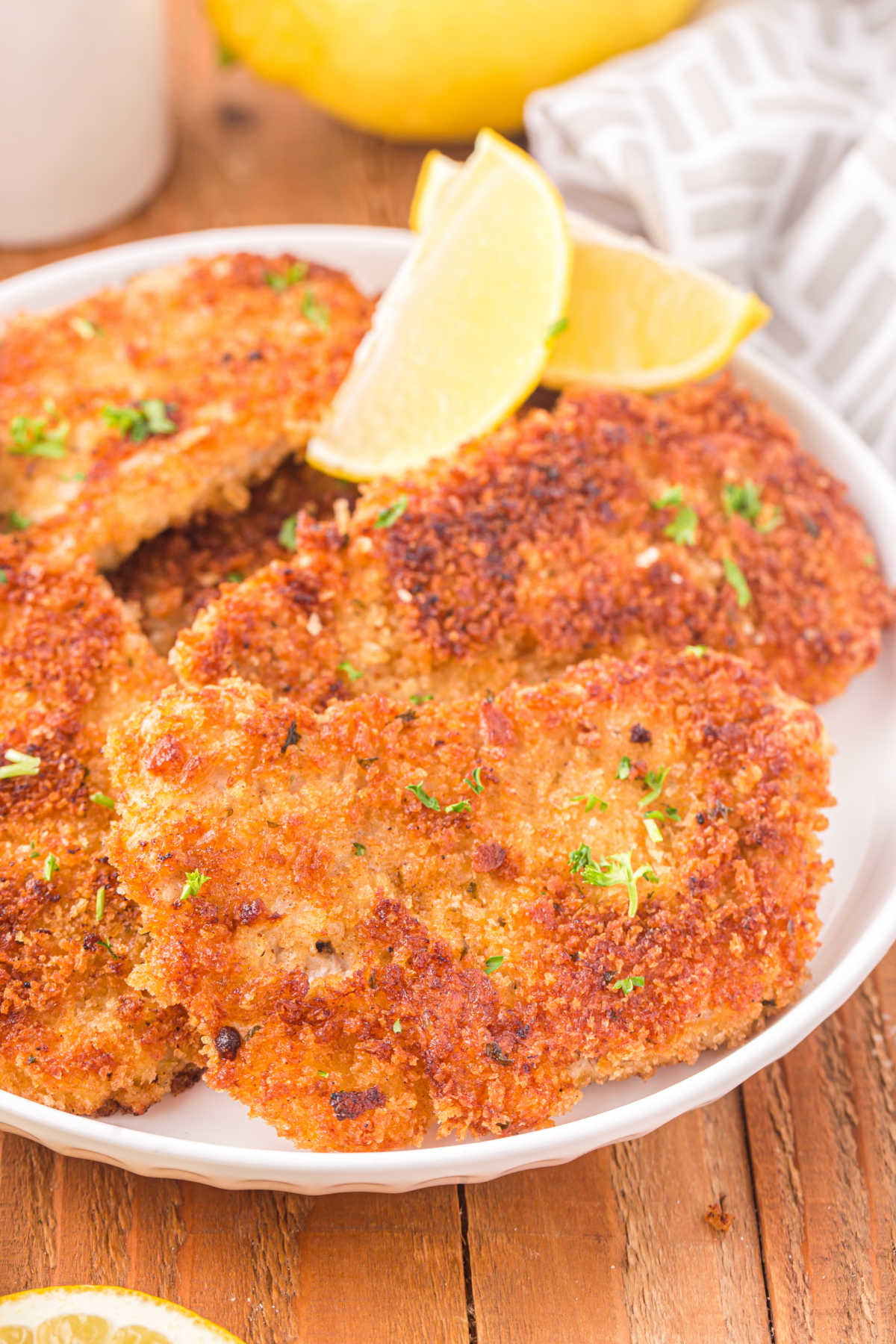 Pork schnitzel on a plate with lemon wedges.