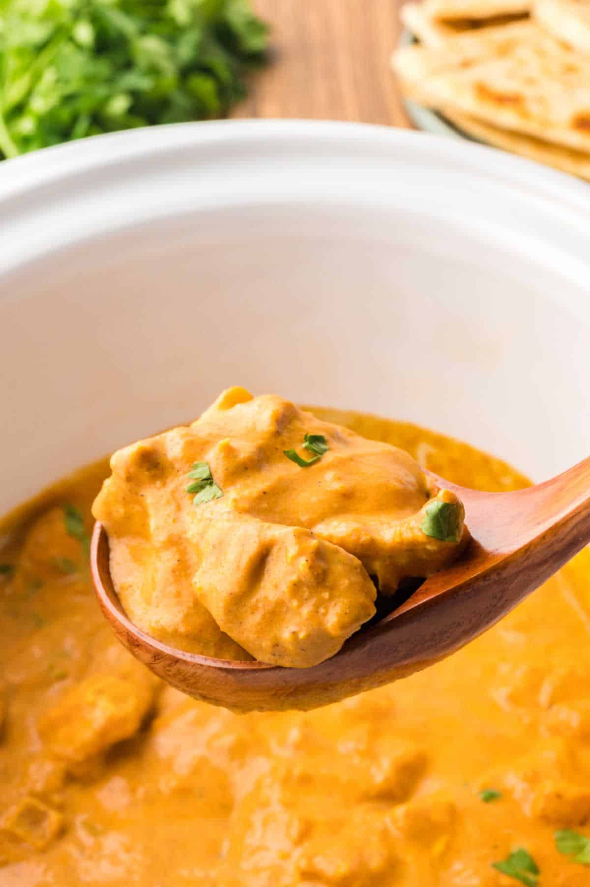 Butter chicken in a wooden ladle.