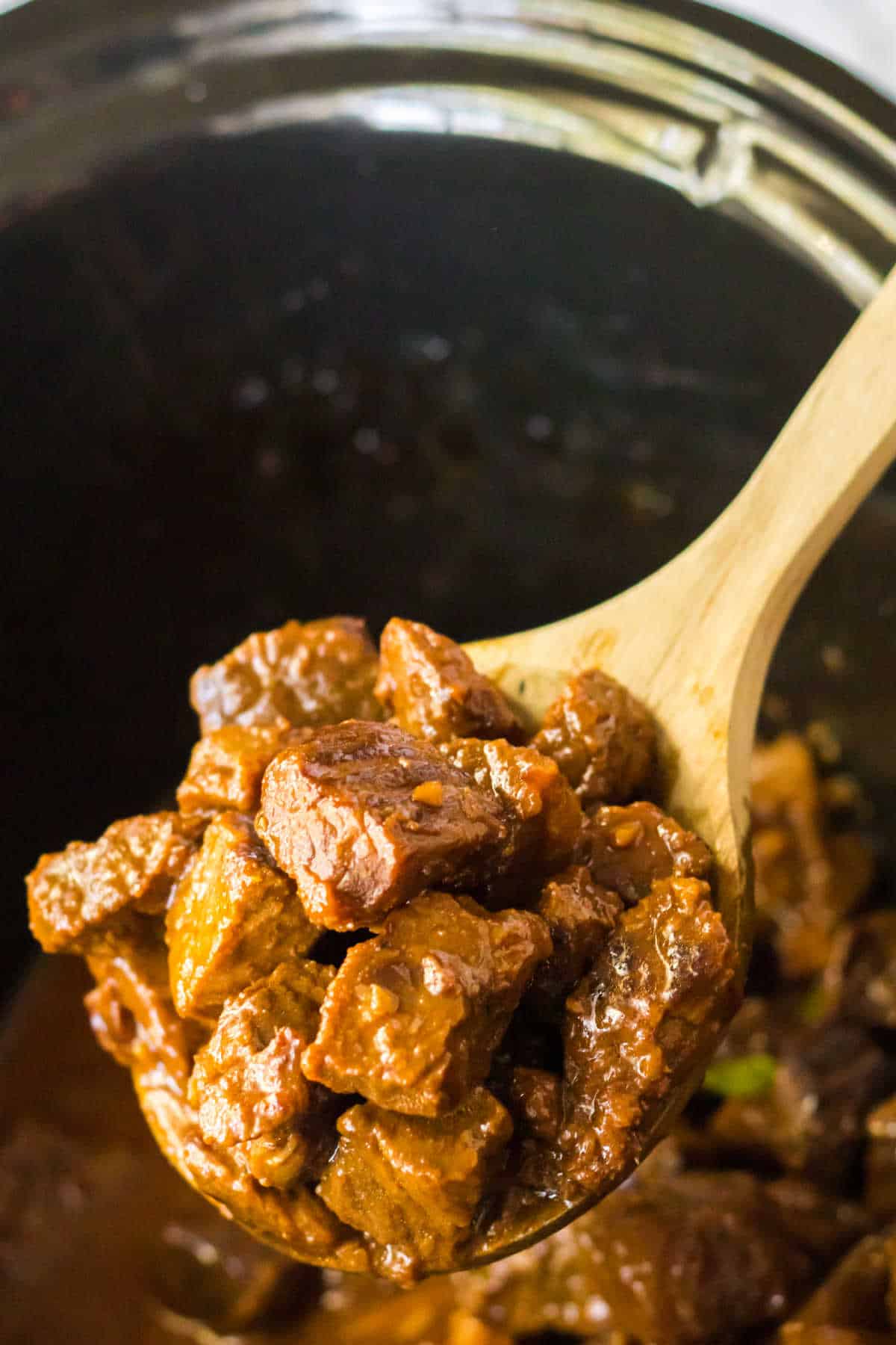 Honey bourbon steak bites on a wooden serving spoon.