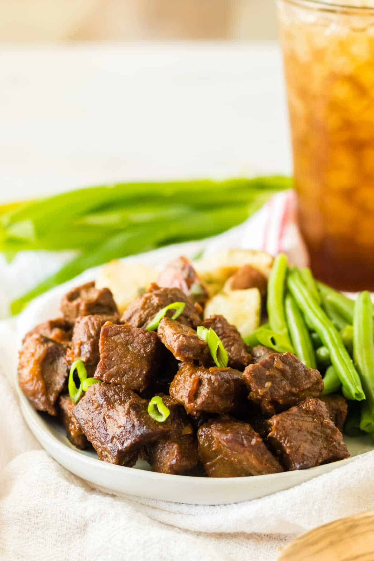 Honey bourbon steak bites on a plate with veggies.