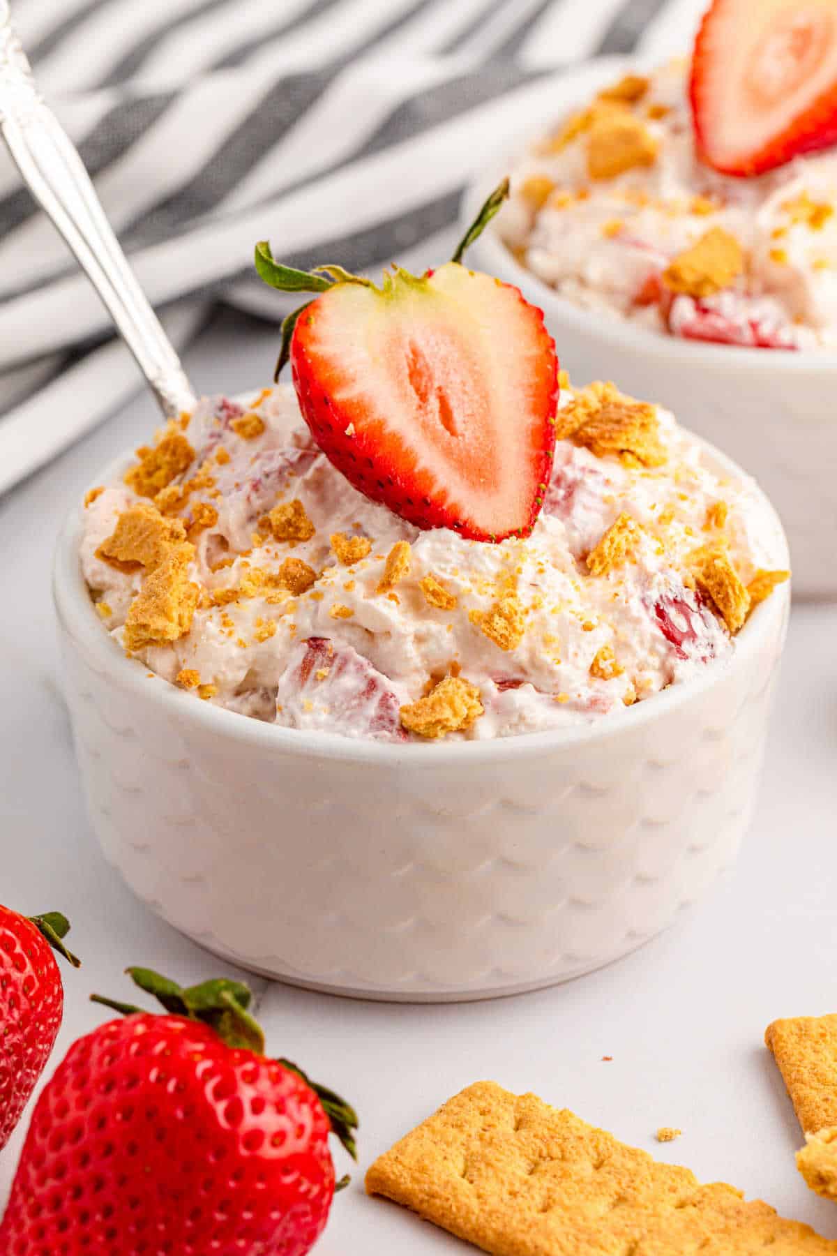 A ramekin of strawberry cheesecake fluff with a spoon.