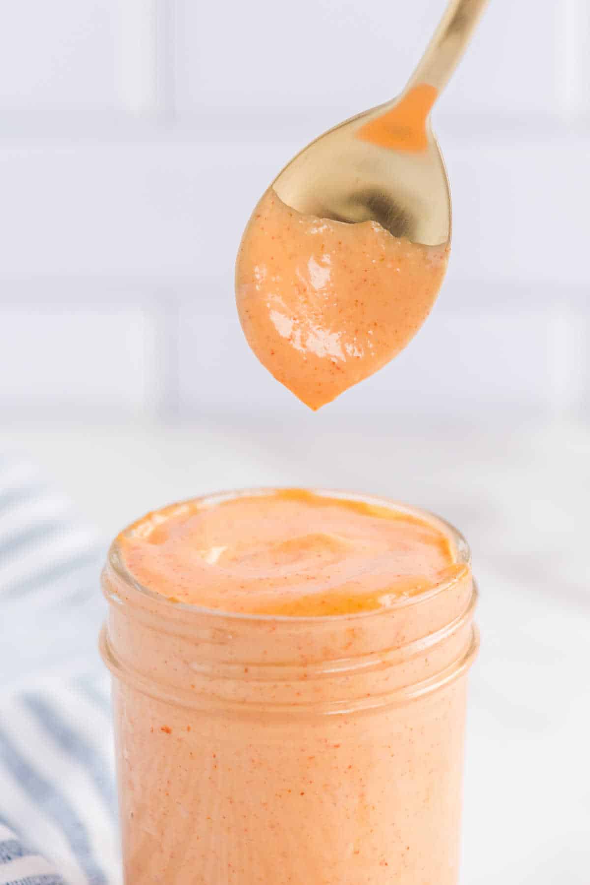 Yum Yum Sauce in a jar with a spoon over top.