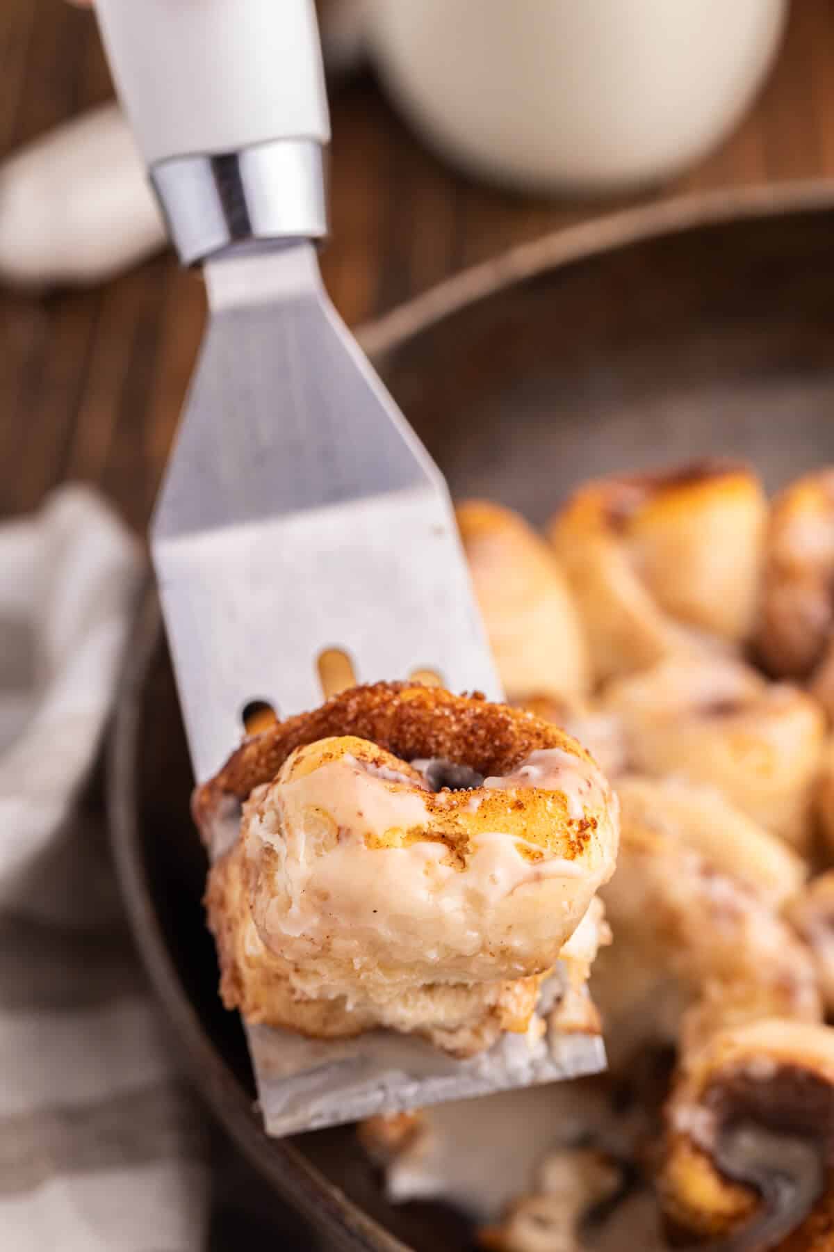 A biscuit cinnamon roll on a spatula.