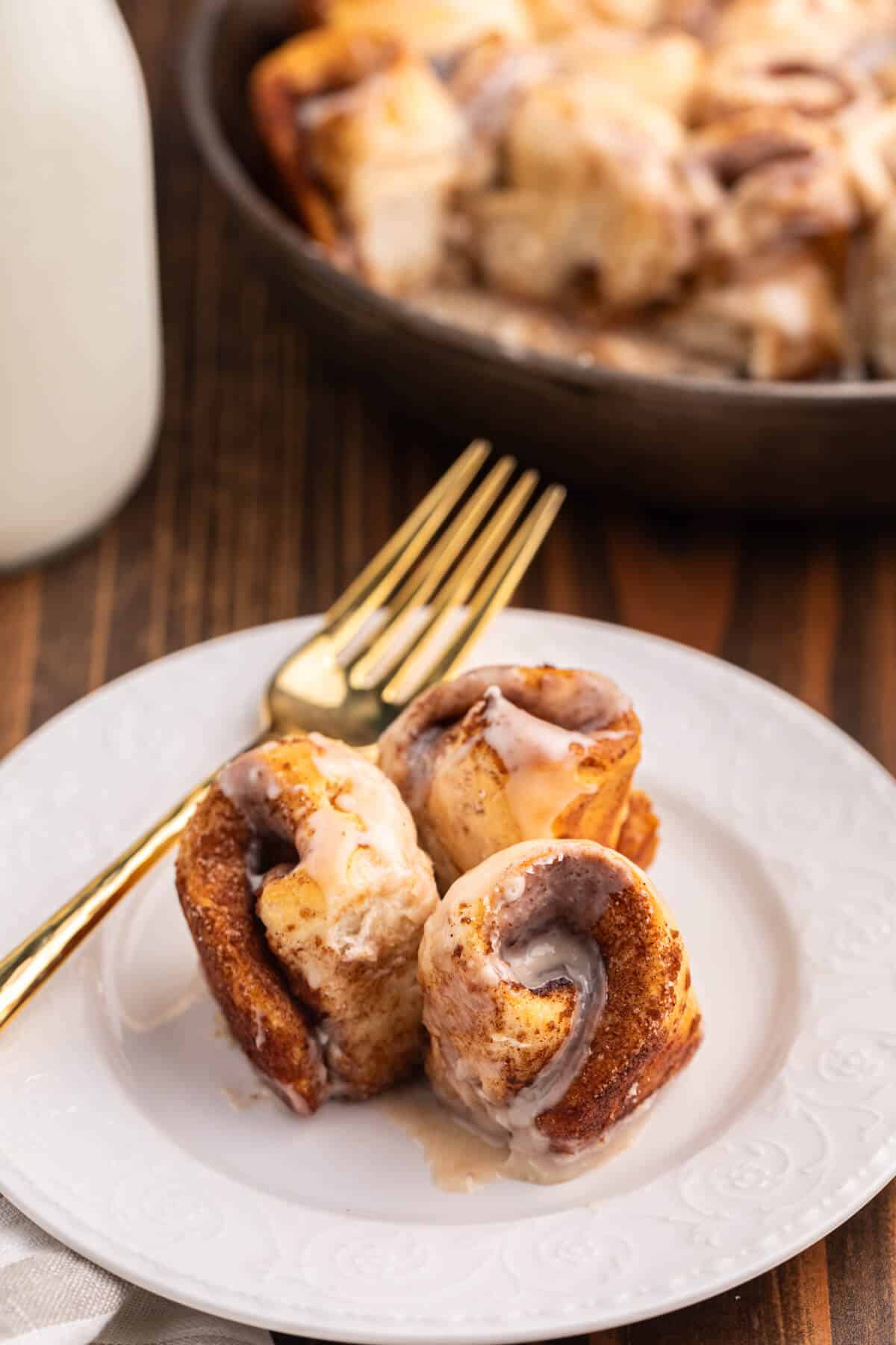 Biscuit cinnamon rolls on a plate with a gold fork.