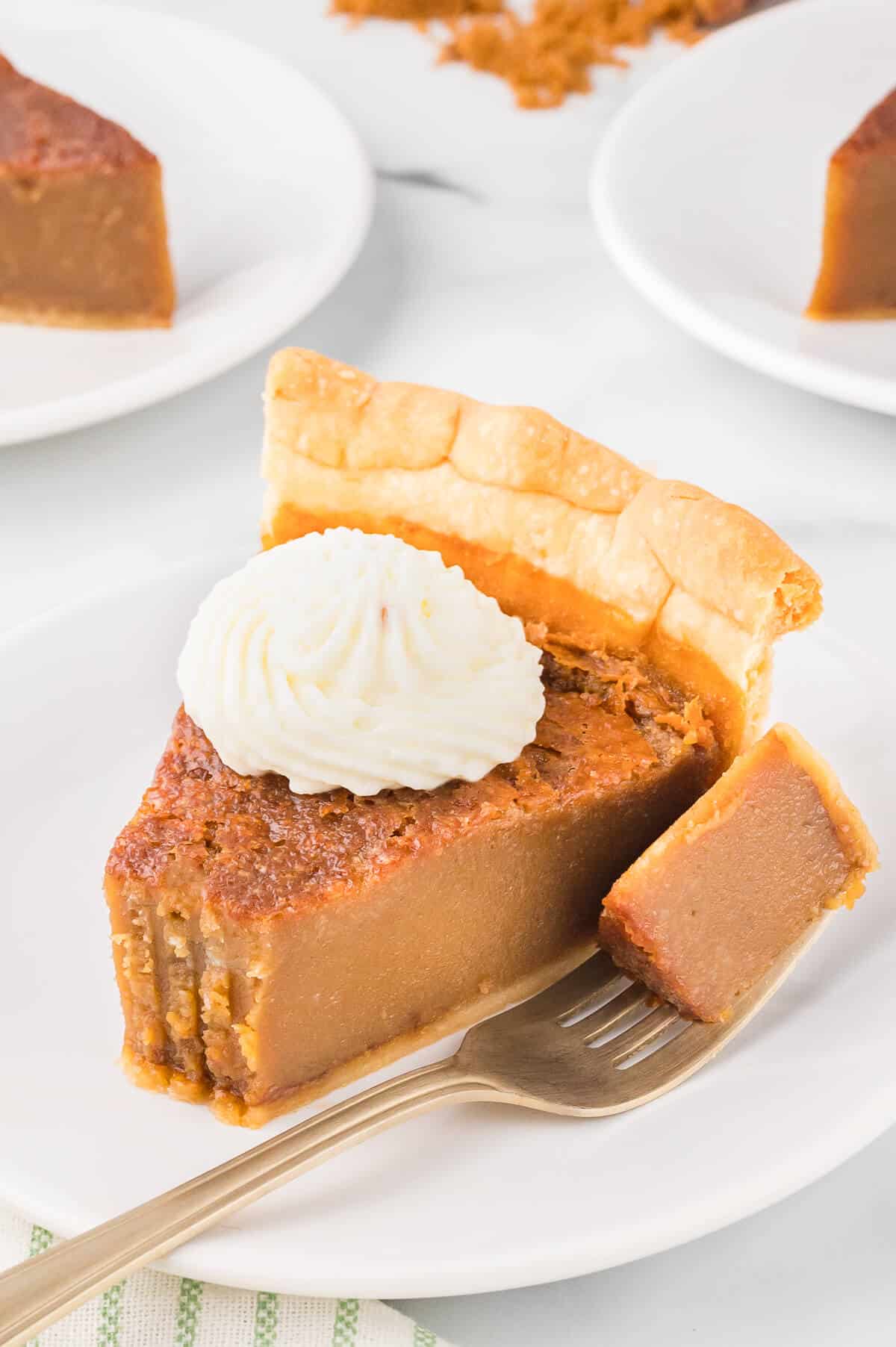 A slice of sugar pie on a plate with a fork with a bite removed.