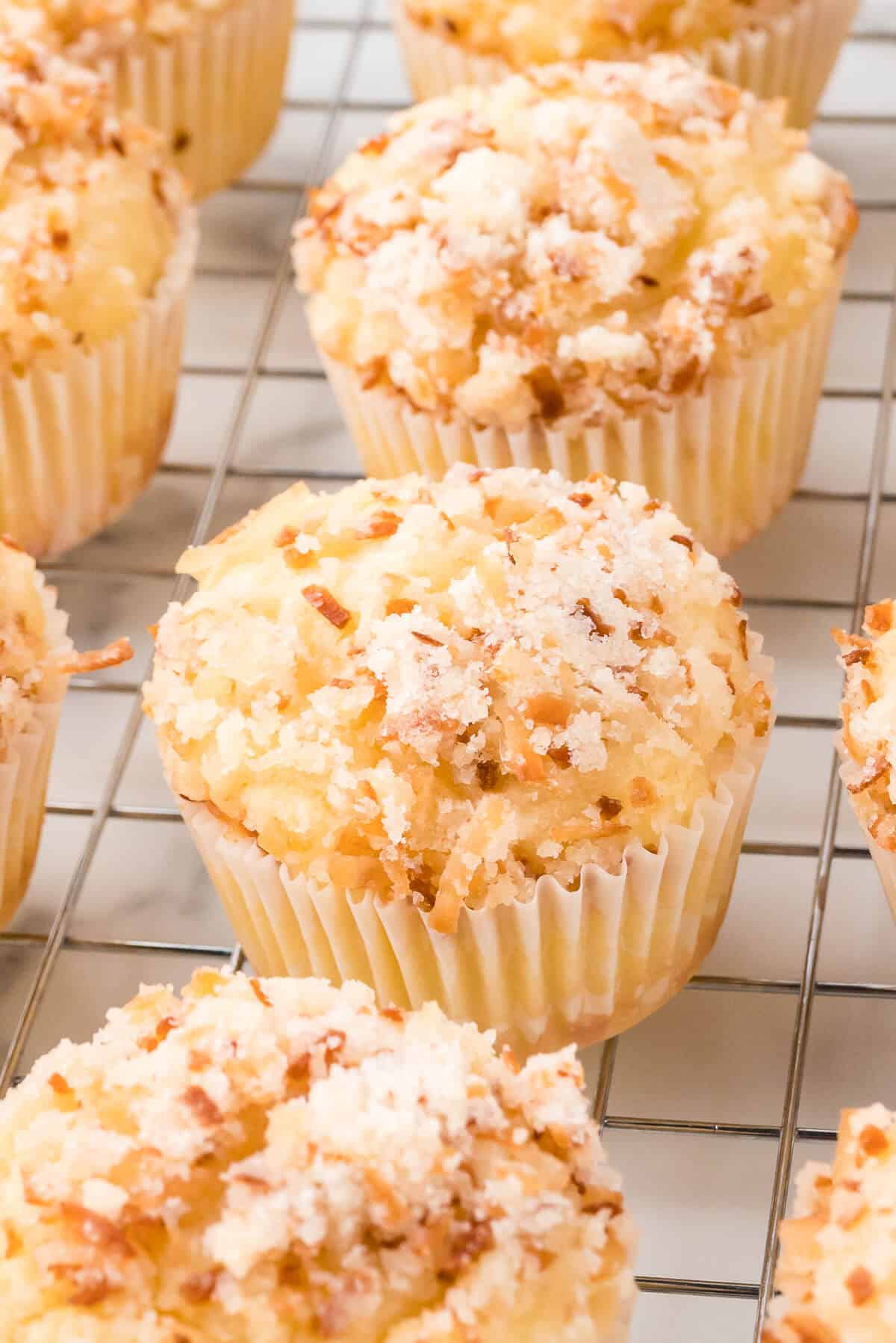 Toasted coconut muffins on a wire rack.