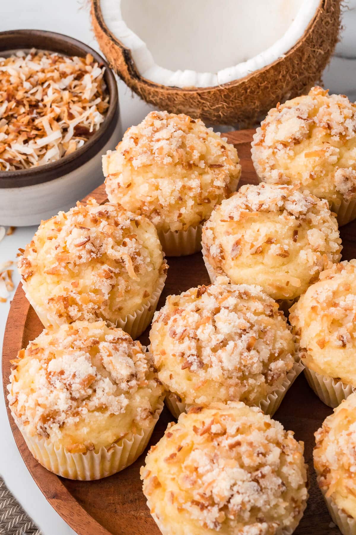 Toasted coconut muffins on a wooden platter.