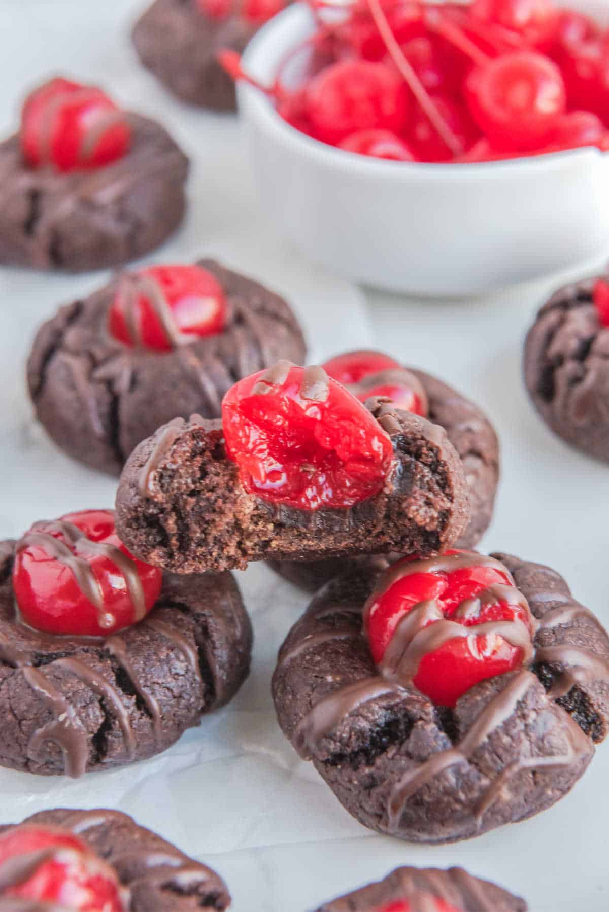A chocolate cherry cookie with a bite out of it.