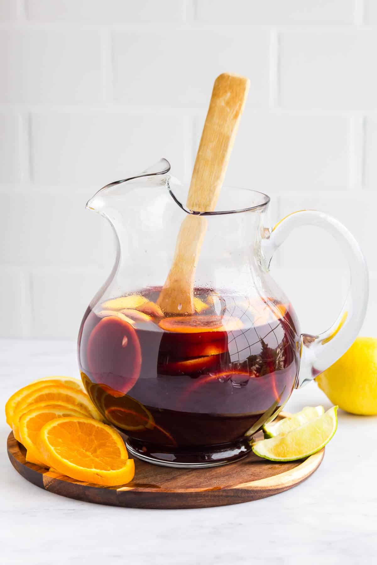 Sangria in a pitcher with a wooden spoon.