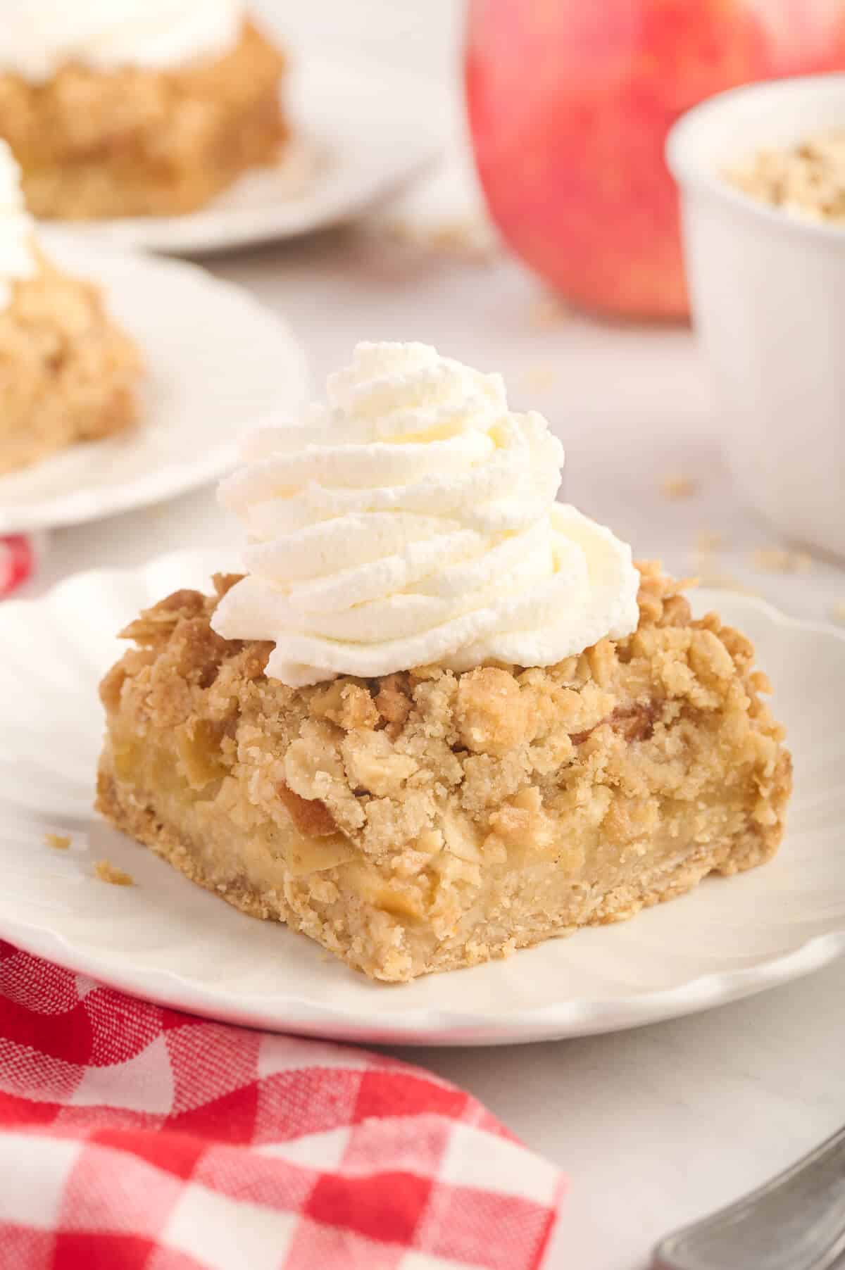 An apple crisp bar topped with whipped cream on a plate.