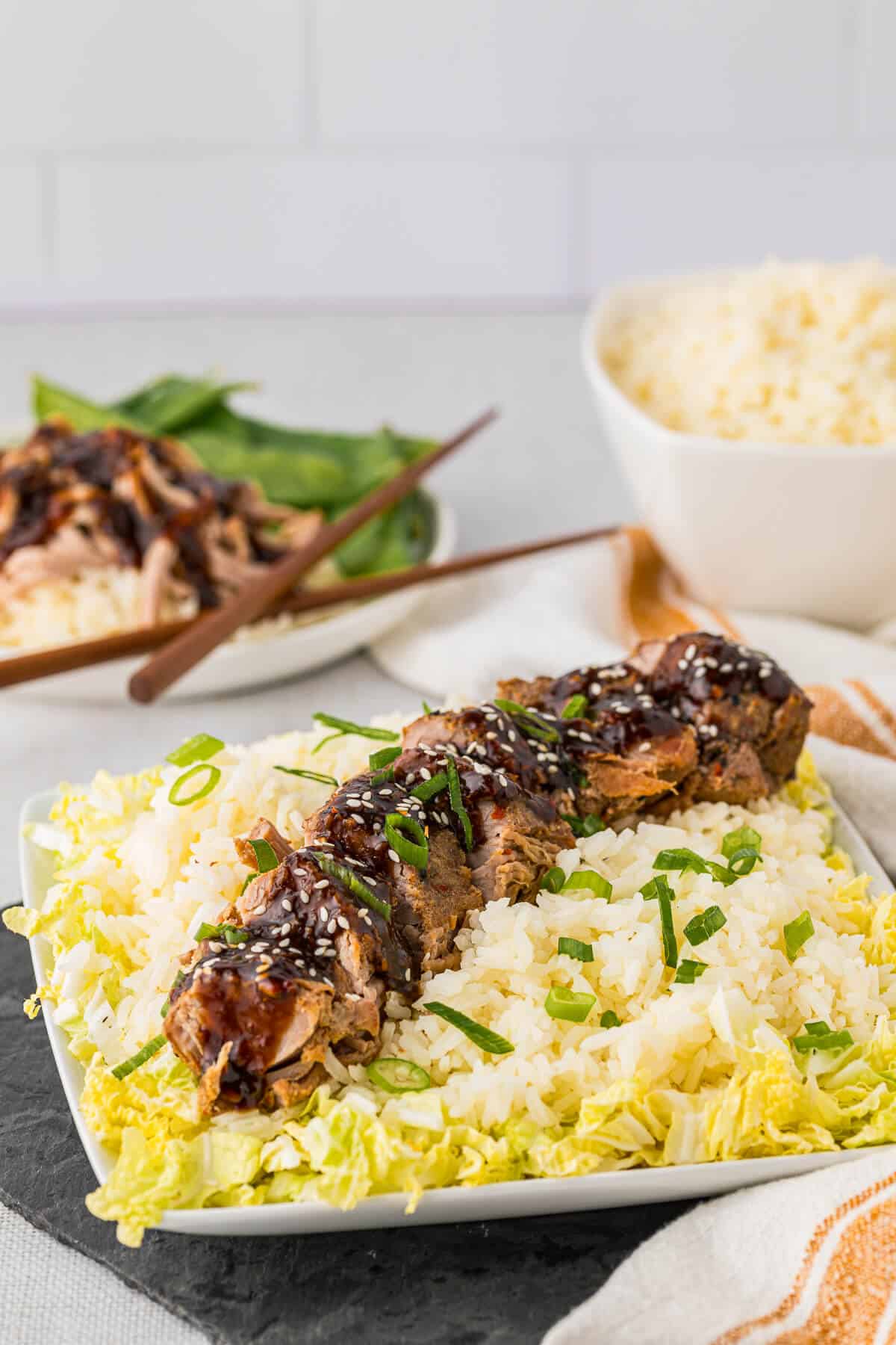 Asian pork tenderloin sliced on a bed of rice and cabbage.