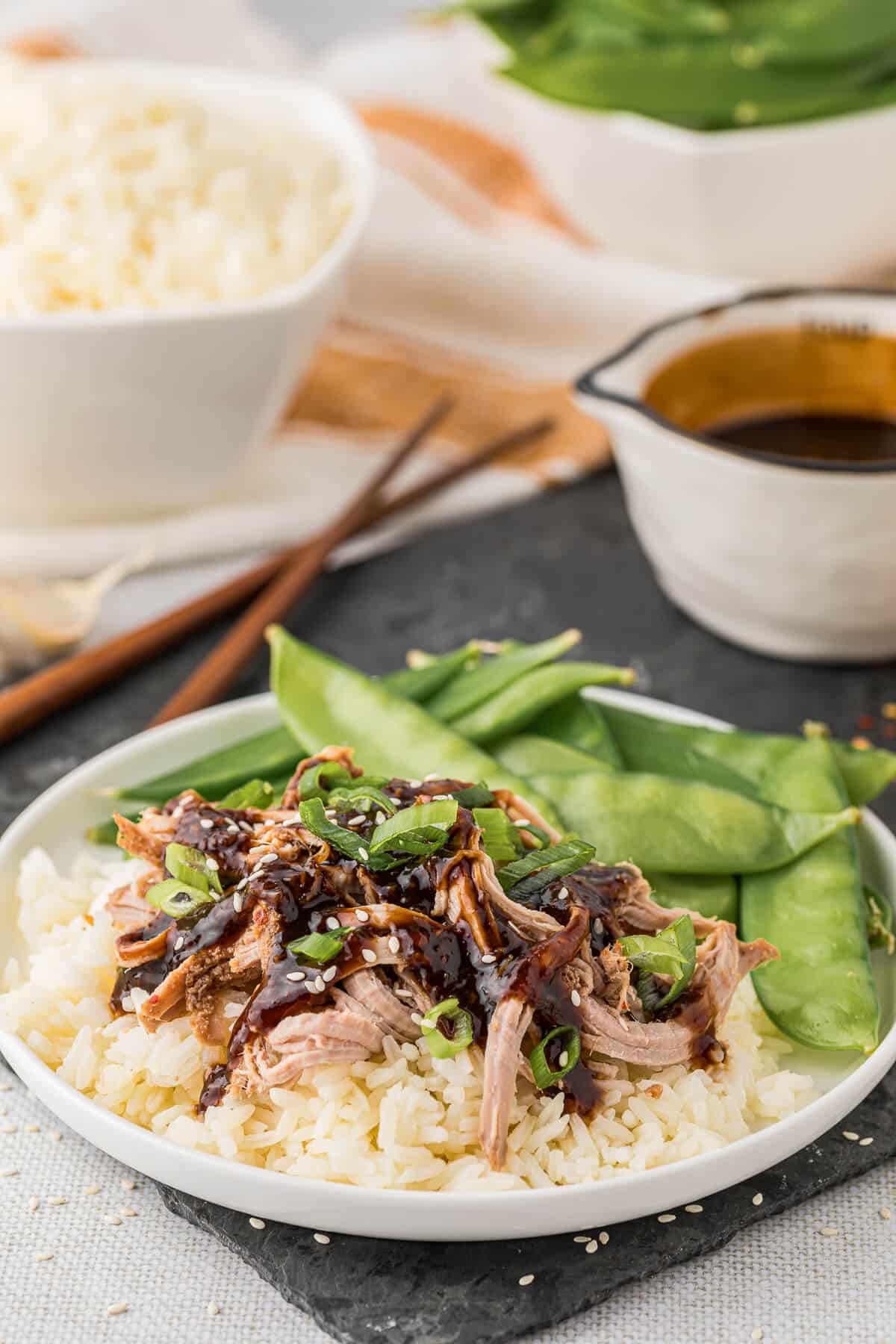 A plate of Asian pork tenderloin with rice and snow peas.