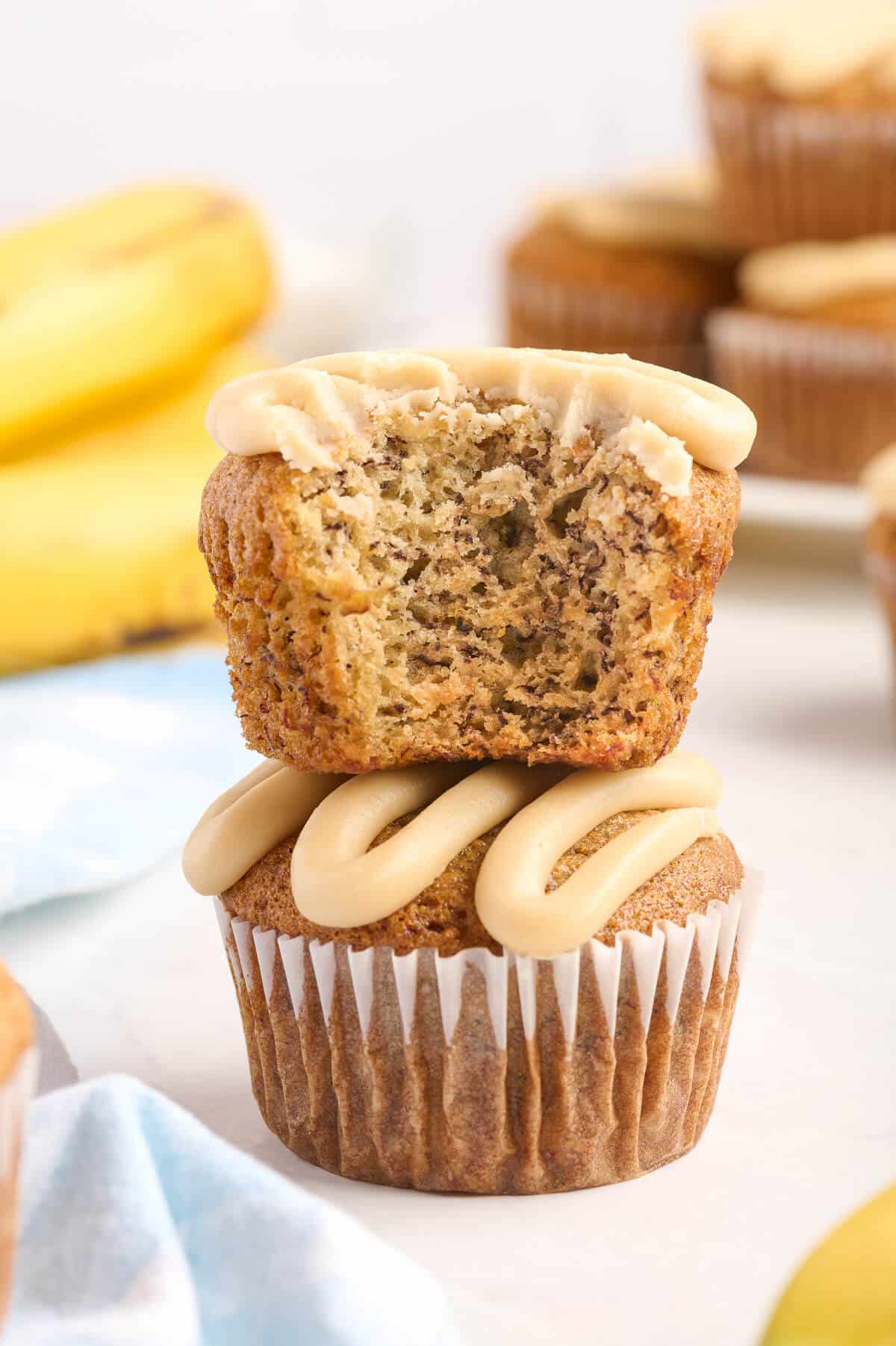 A stack of caramel banana muffins with a bite out of the top muffin.