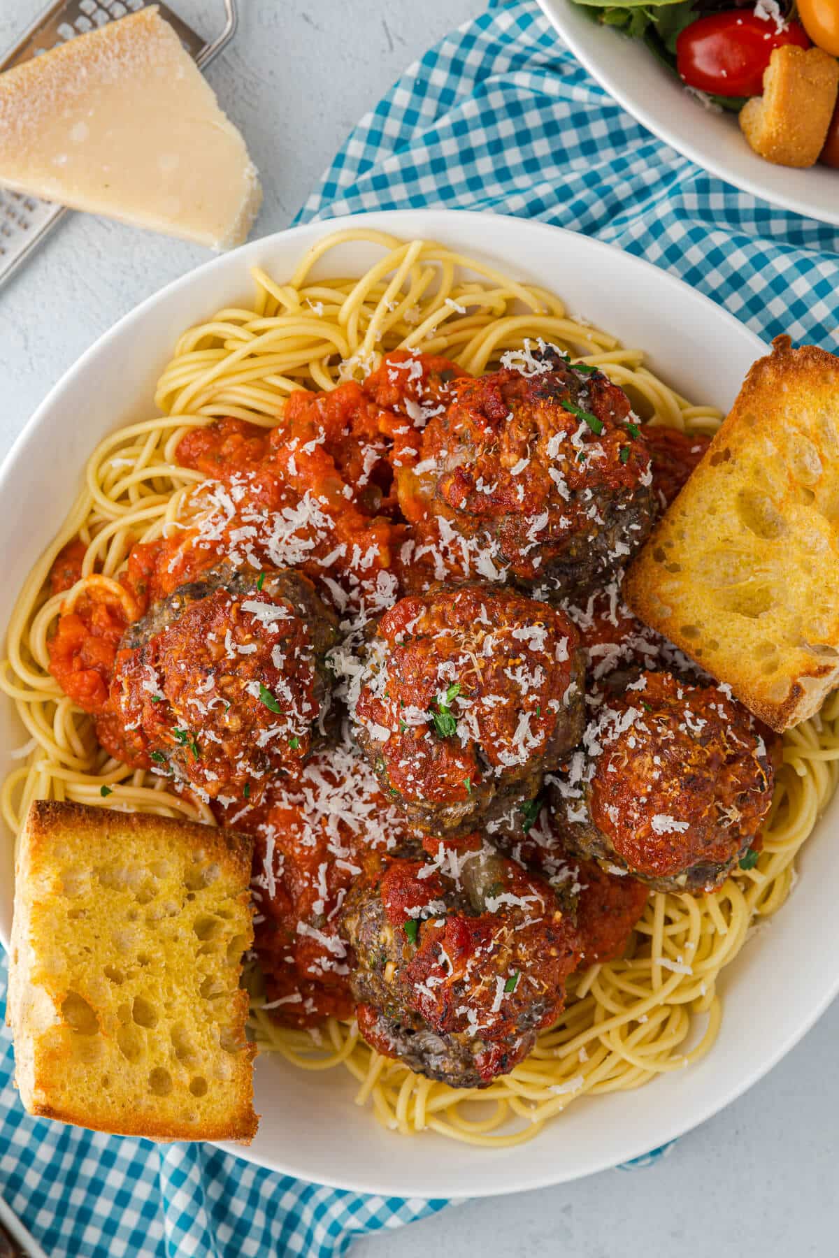 A plate of spaghetti with cheesy meatballs and garlic bread.