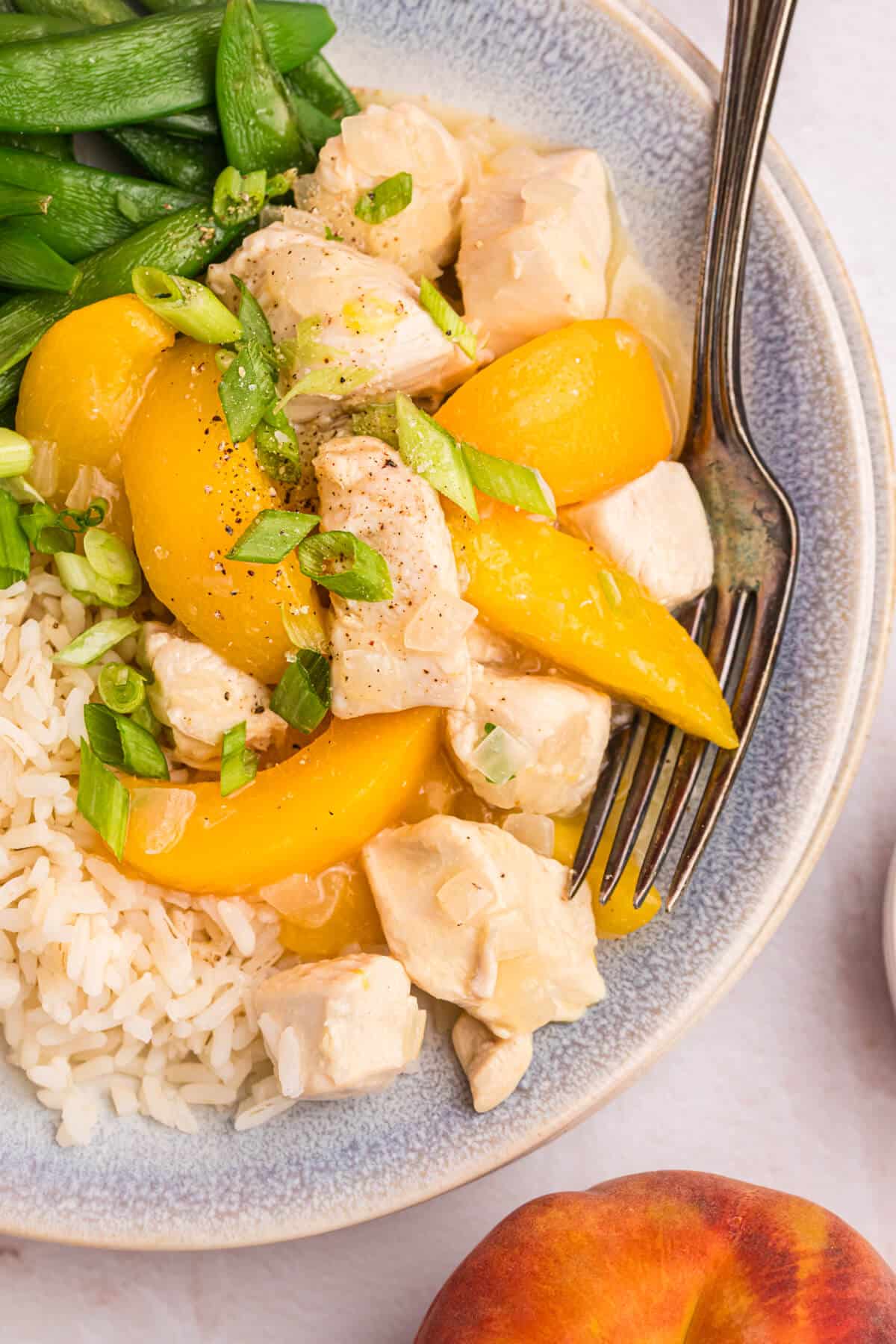 Peach chicken on a plate with a fork.